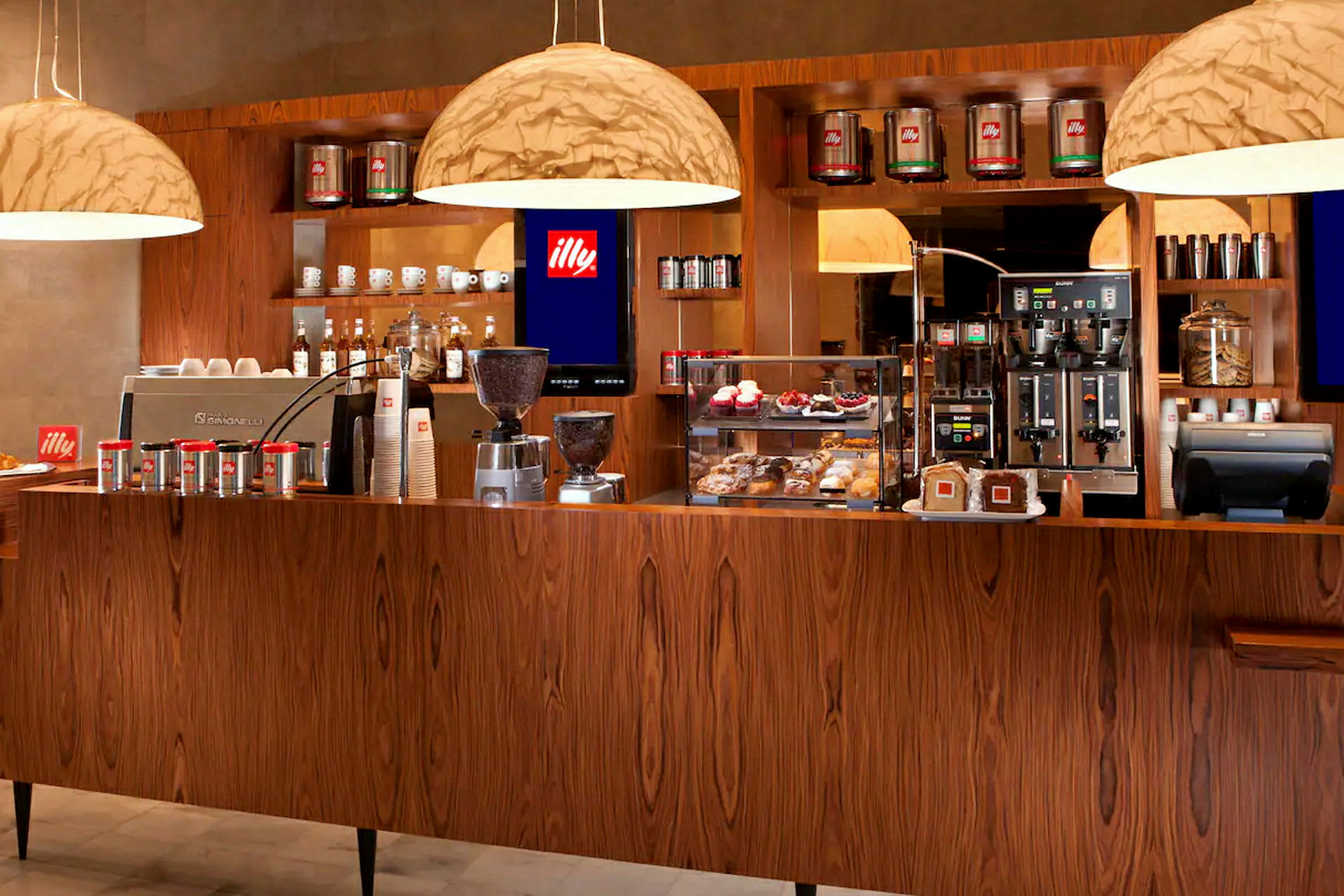 En kafé med espressomaskiner, kaffebokser og bakverk på en treinnredet disk. (AI-generert tekst)