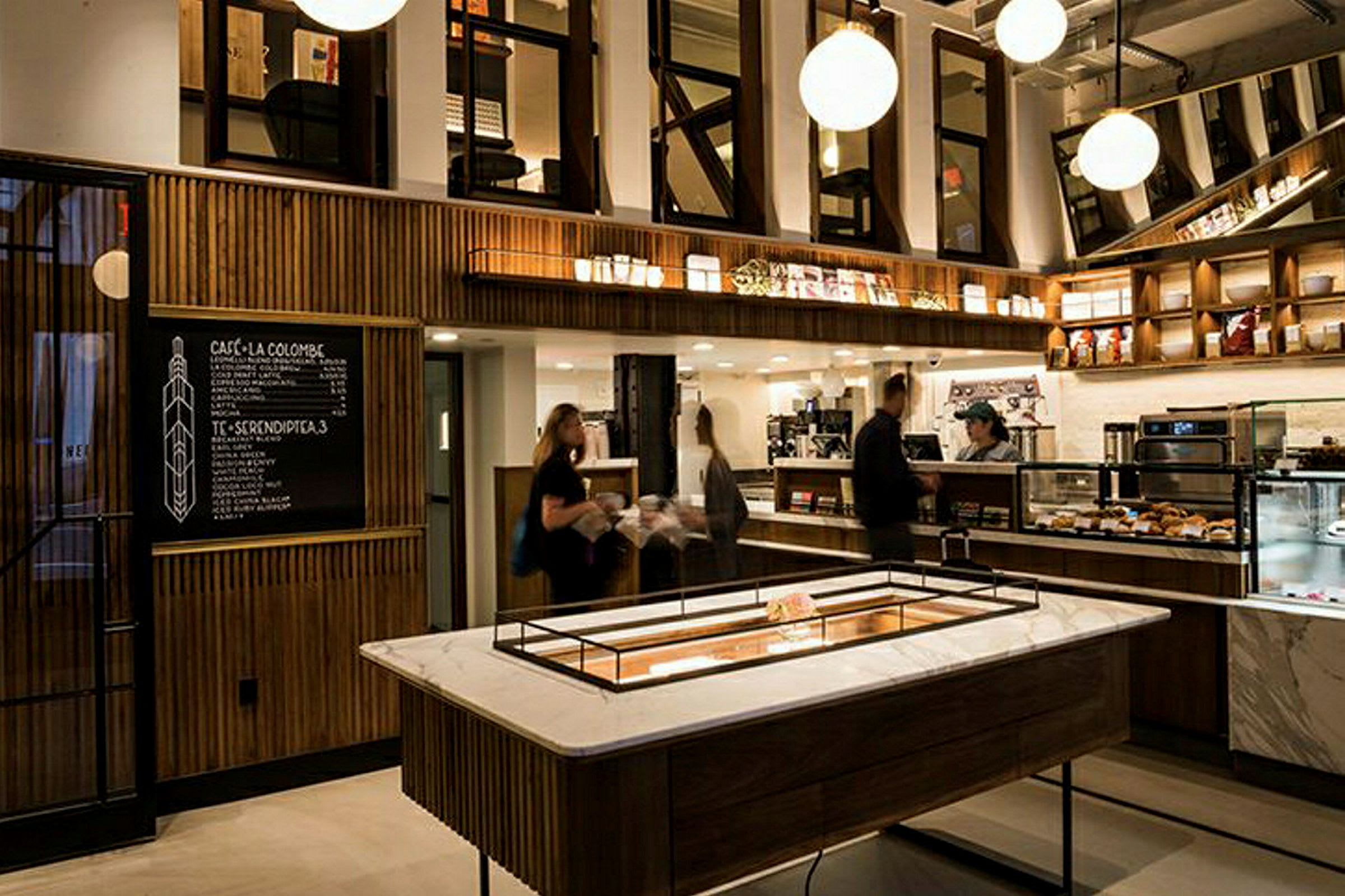 Bilde av en moderne kaffebar med elegant interiør, veggmonterte hyller og en meny på en svart tavle. (AI-generert tekst)