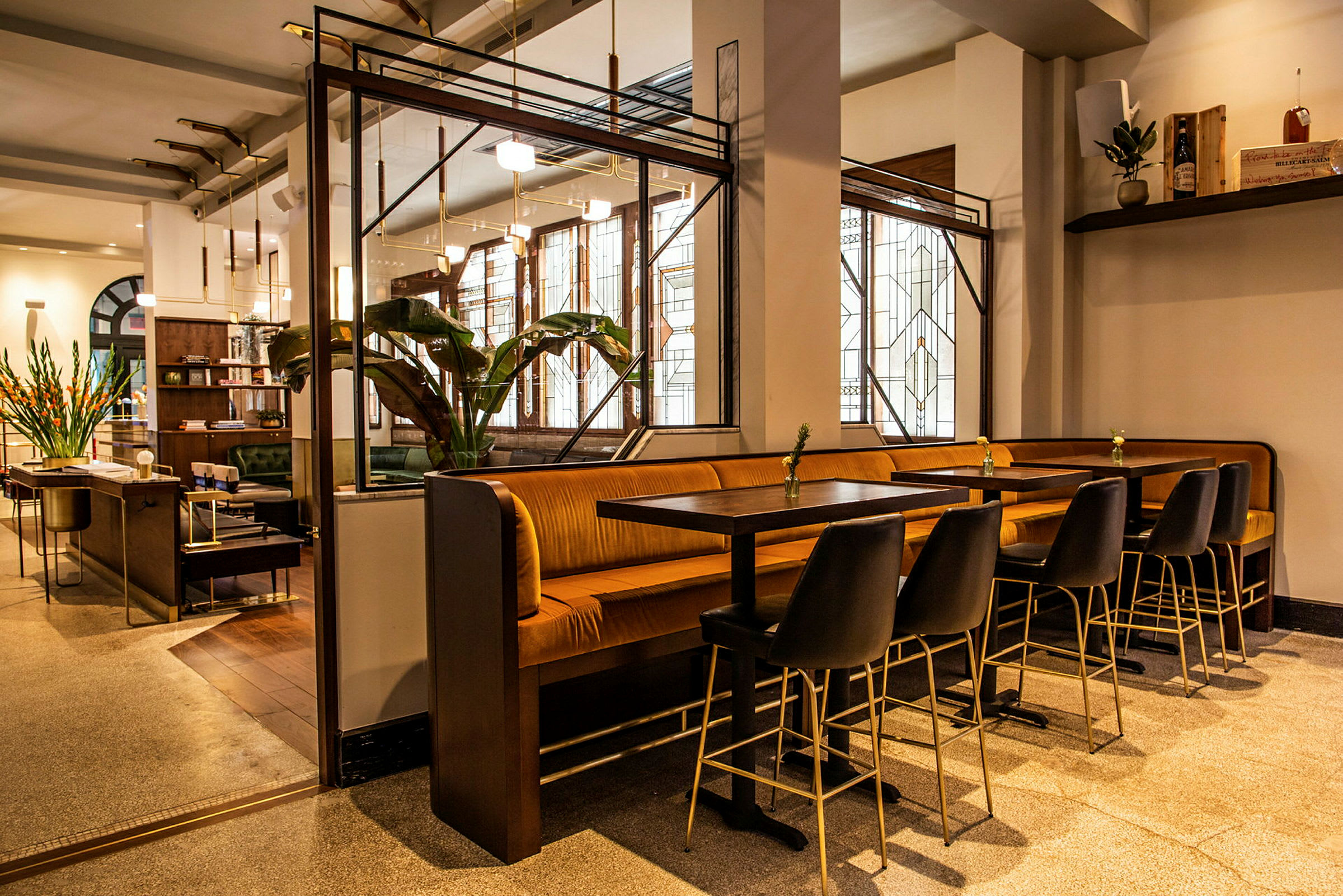 Et moderne kafé med bord, stoler og benker samt dekorative grønne planter og stilfull belysning. (AI-generert tekst)