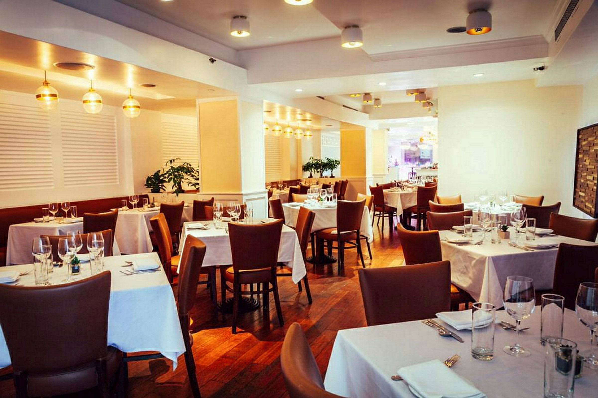 En elegant restaurant med bord dekket og brune stoler. (AI-generert tekst)