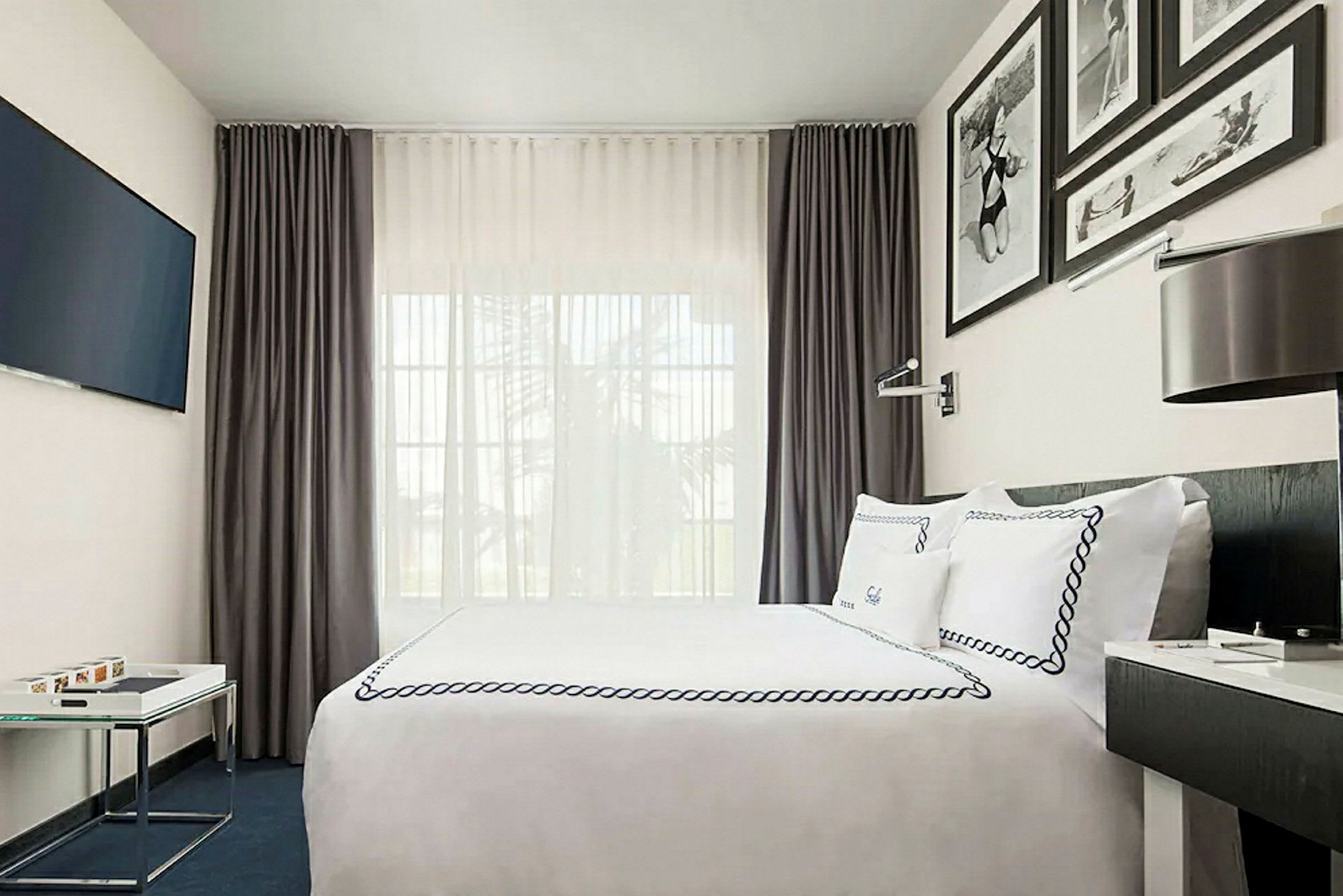 Moderne møblert hotellrom med seng, veggdekorasjoner og gardiner. (AI-generert tekst)