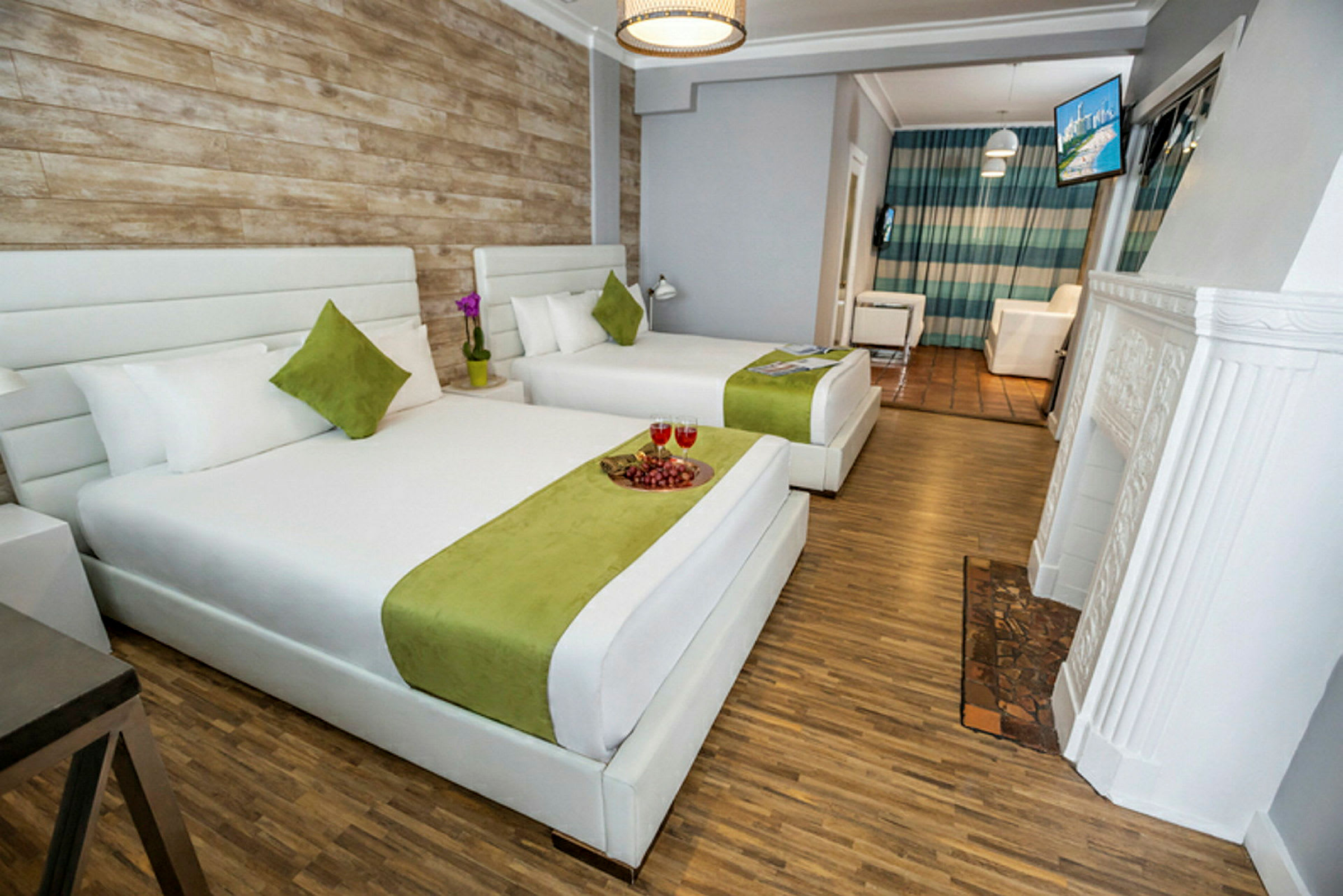 Hotellrom med to store senger med hvitt og grønt sengetøy, et tregulv og en vegg i rustikk stil. (AI-generert tekst)