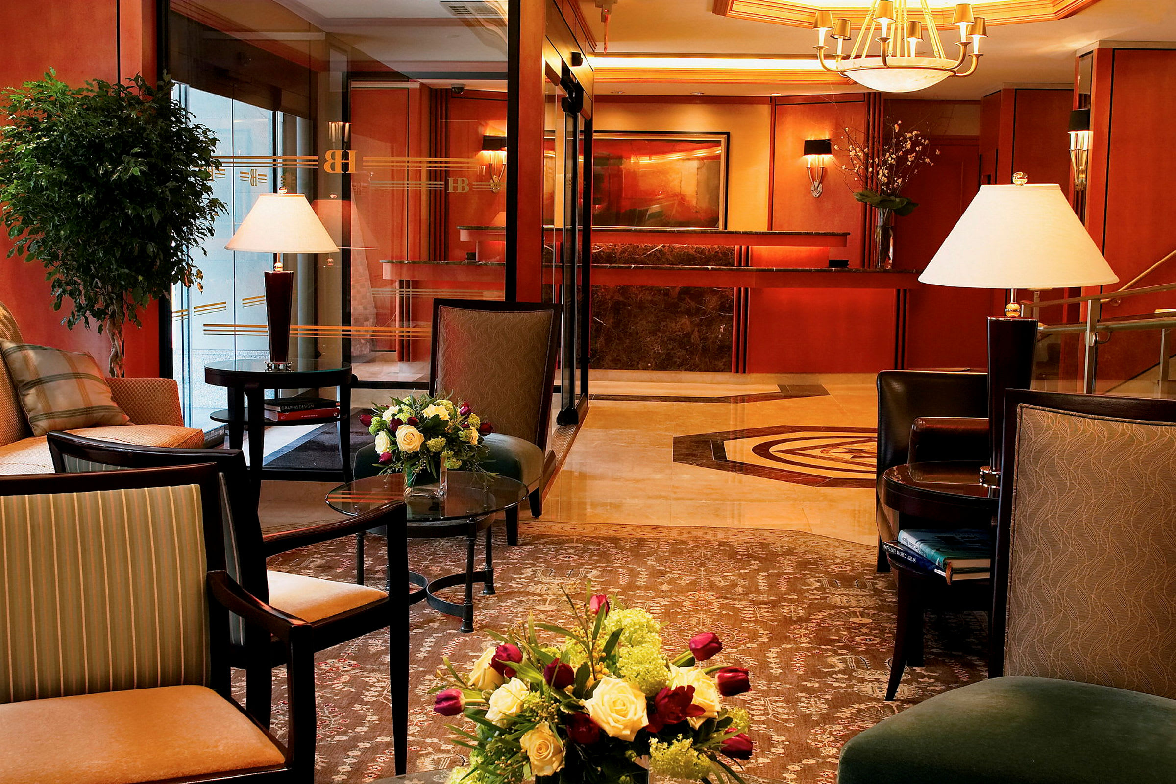 Et smakfullt innredet hotellobbyområde med møblert sitteplasser, interiørdetaljer, blomsterarrangementer og resepsjonen i bakgrunnen. (AI-generert tekst)