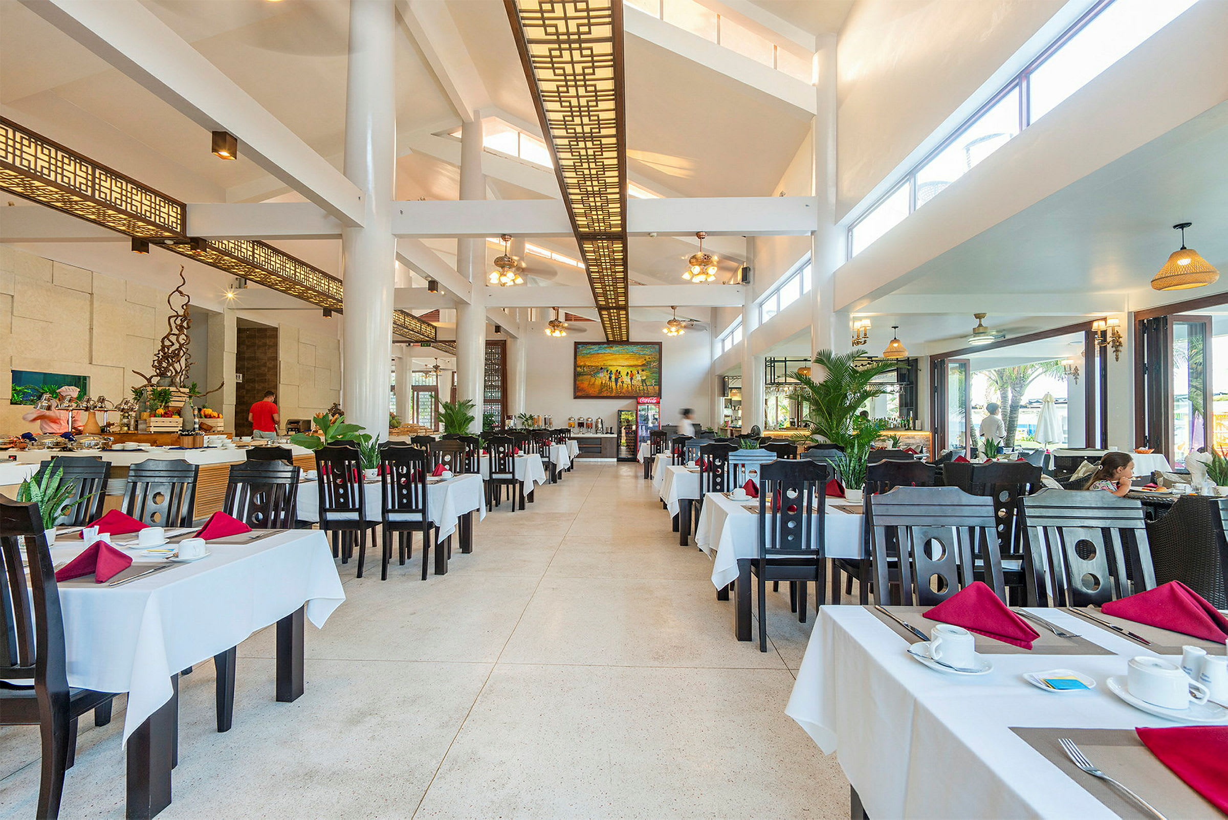 En romslig restaurant med mange bord med hvite duker. (AI-generert tekst)