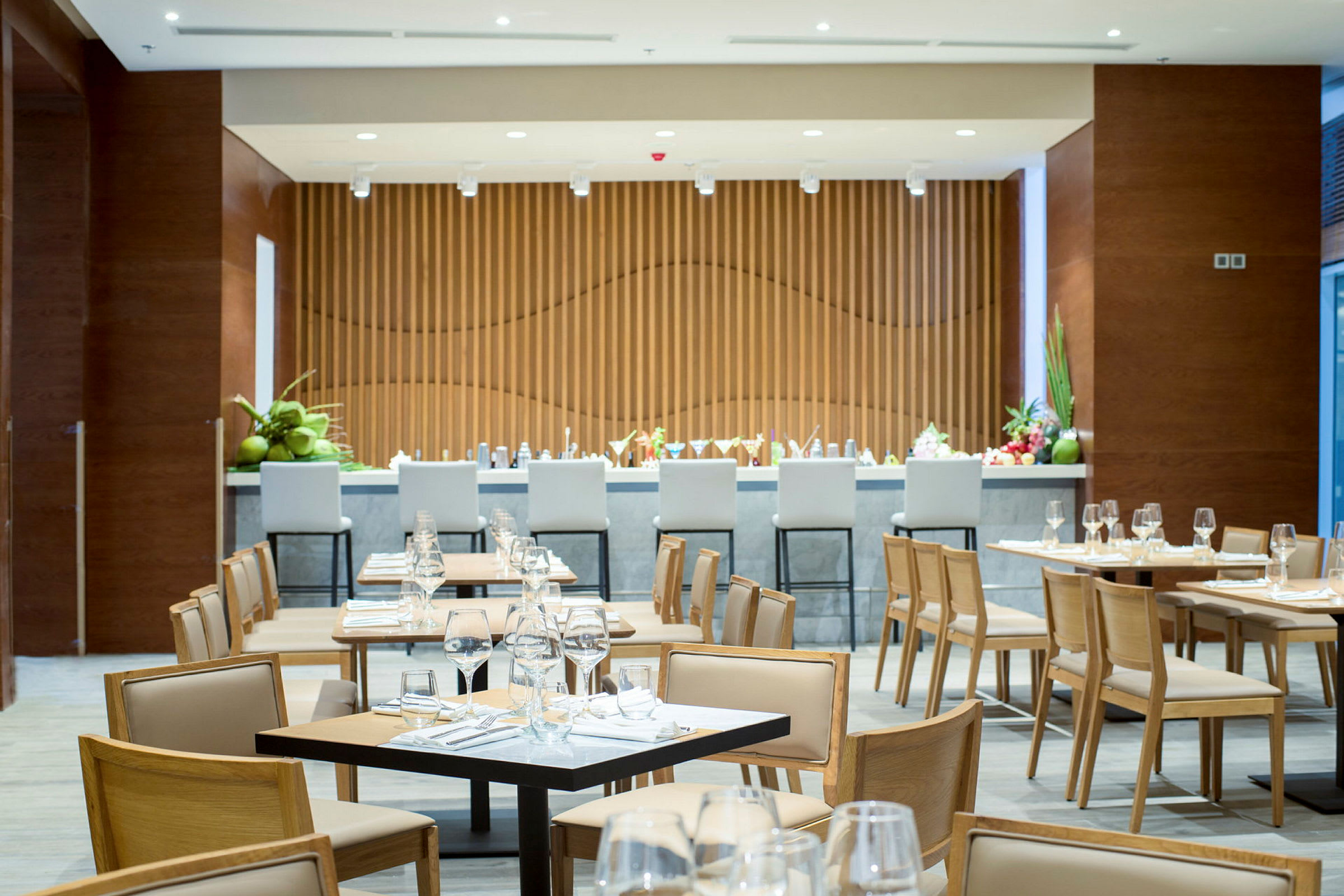 En restaurant med dekkede bord og stoler samt en bardisk i bakgrunnen. (AI-generert tekst)