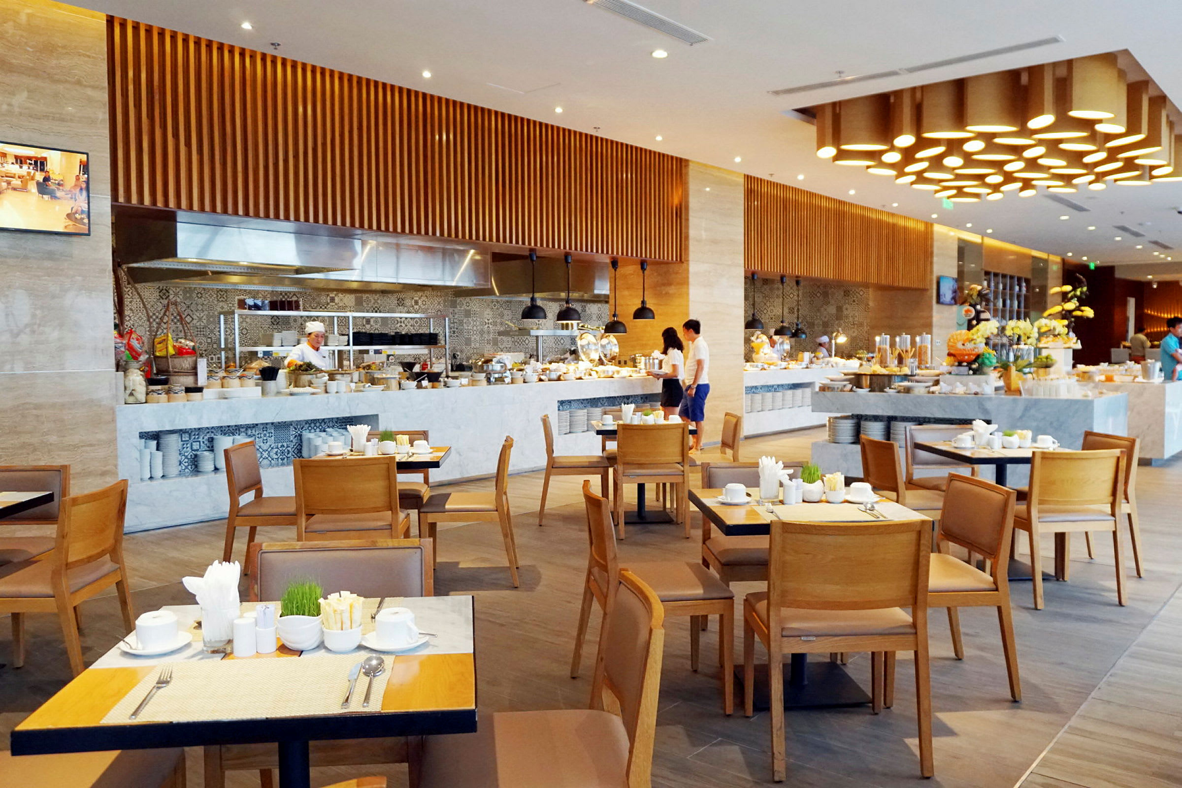 En restaurant med dekkede bord, kjøkkenutstyr og personale som forbereder måltider. (AI-generert tekst)