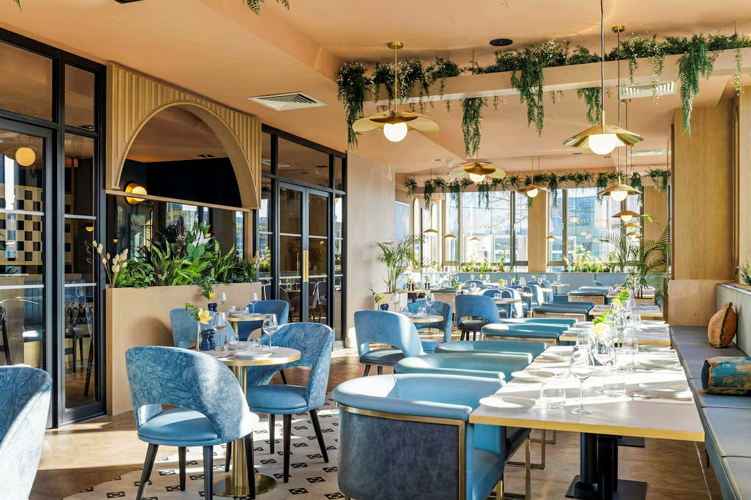 En restaurant med blå stoler, bord og plantedekorasjoner. (AI-generert tekst)