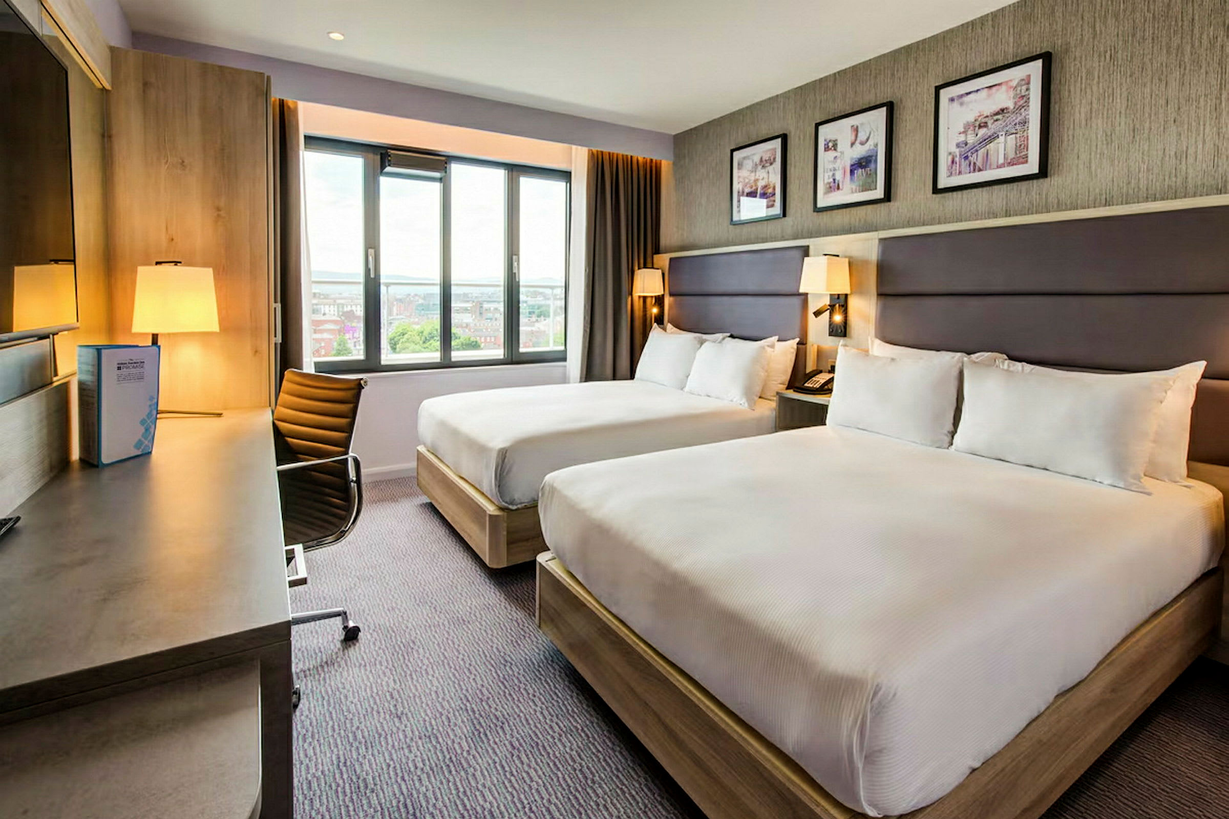 Hotellrom med to senger, skrivebord og vindu. (AI-generert tekst)