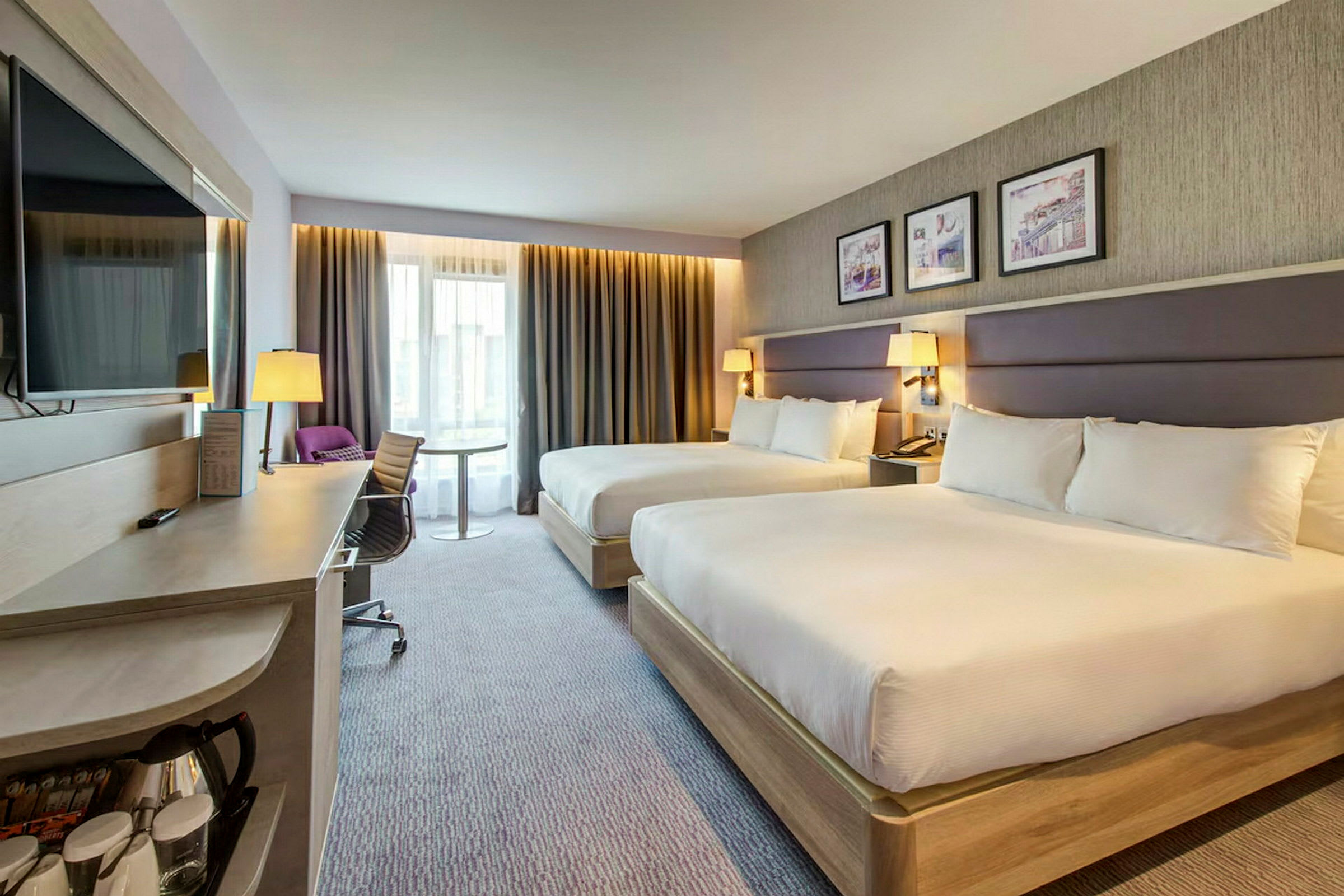 Hotellrom med to brede senger, skrivebord og moderne innredning. (AI-generert tekst)