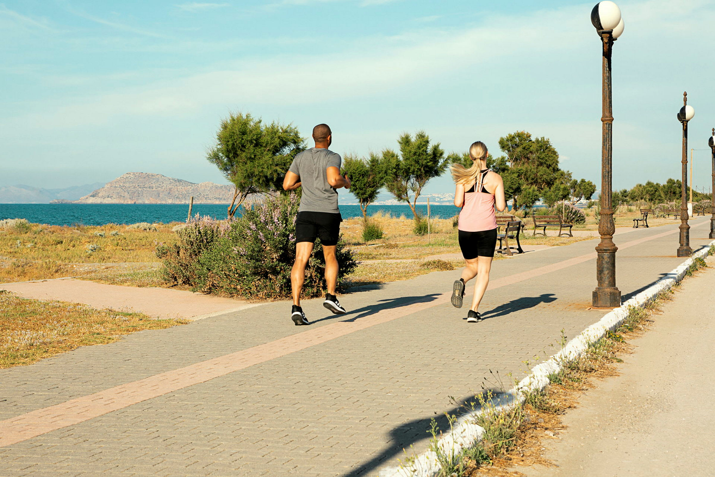To personer jogger på en gangvei ved havet. (AI-generert tekst)
