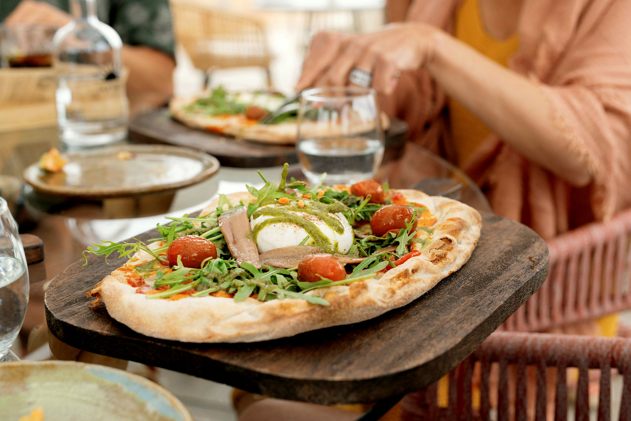 Et nærbilde av en pizza med ruccola, cherrytomater og mozzarella. (AI-generert tekst)