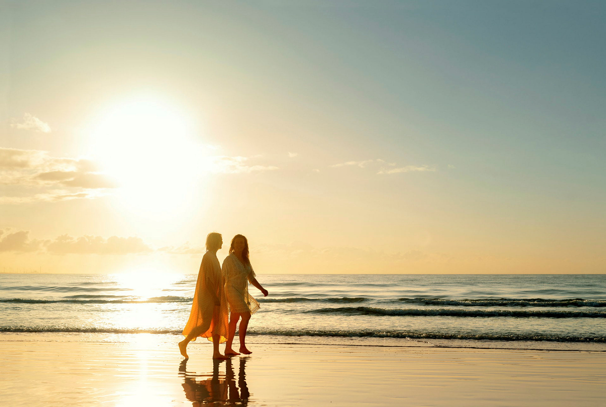 To personer går på en strand ved solnedgang. (AI-generert tekst)