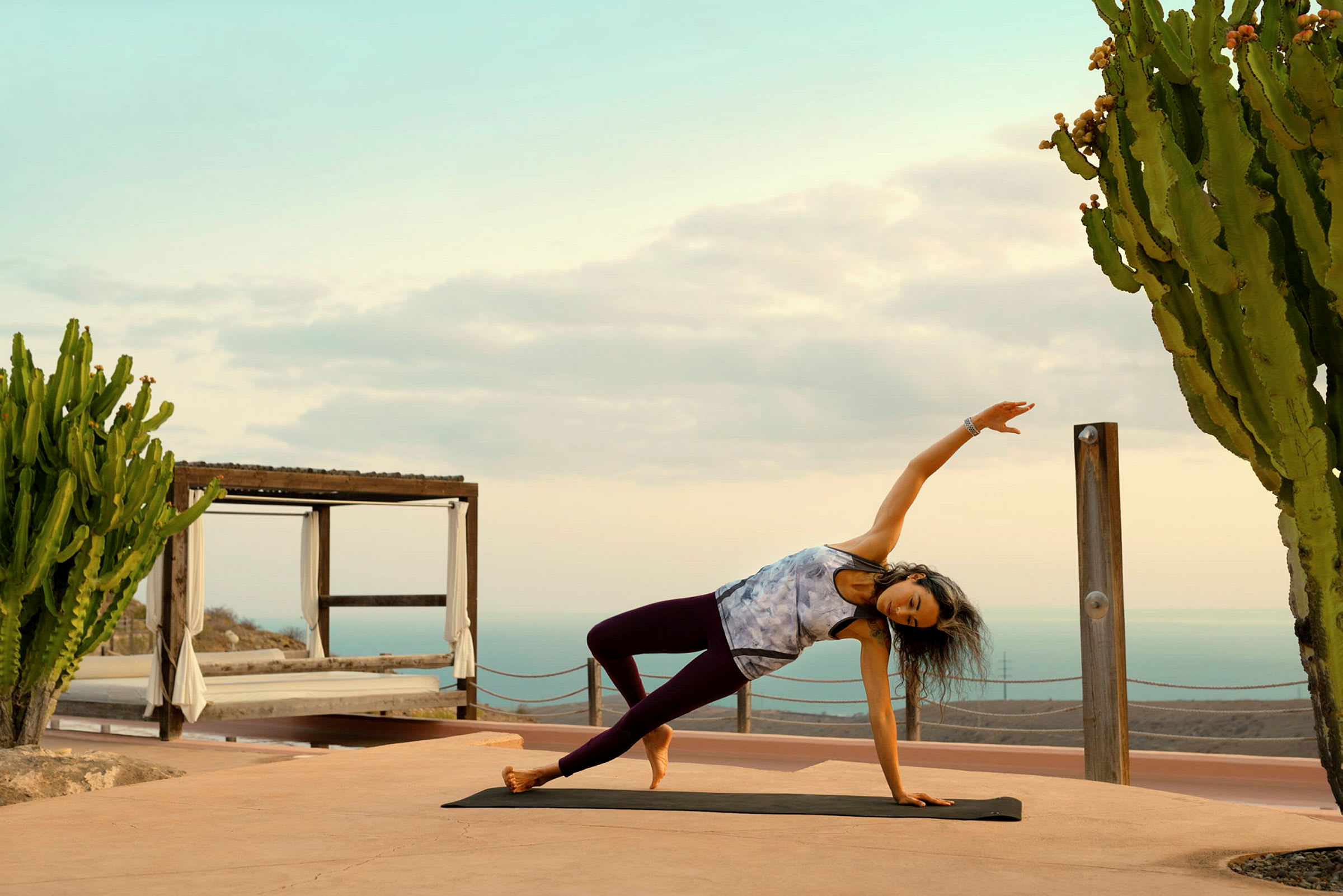 Person gjør yoga på en matte utendørs ved siden av en kaktus. (AI-generert tekst)