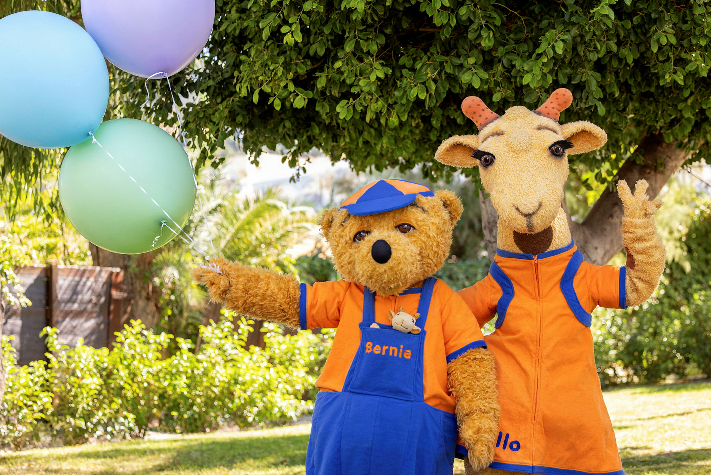 To dyrekarakterer i oransje klær står ute ved et tre, med ballonger synlige til venstre. (AI-generert tekst)
