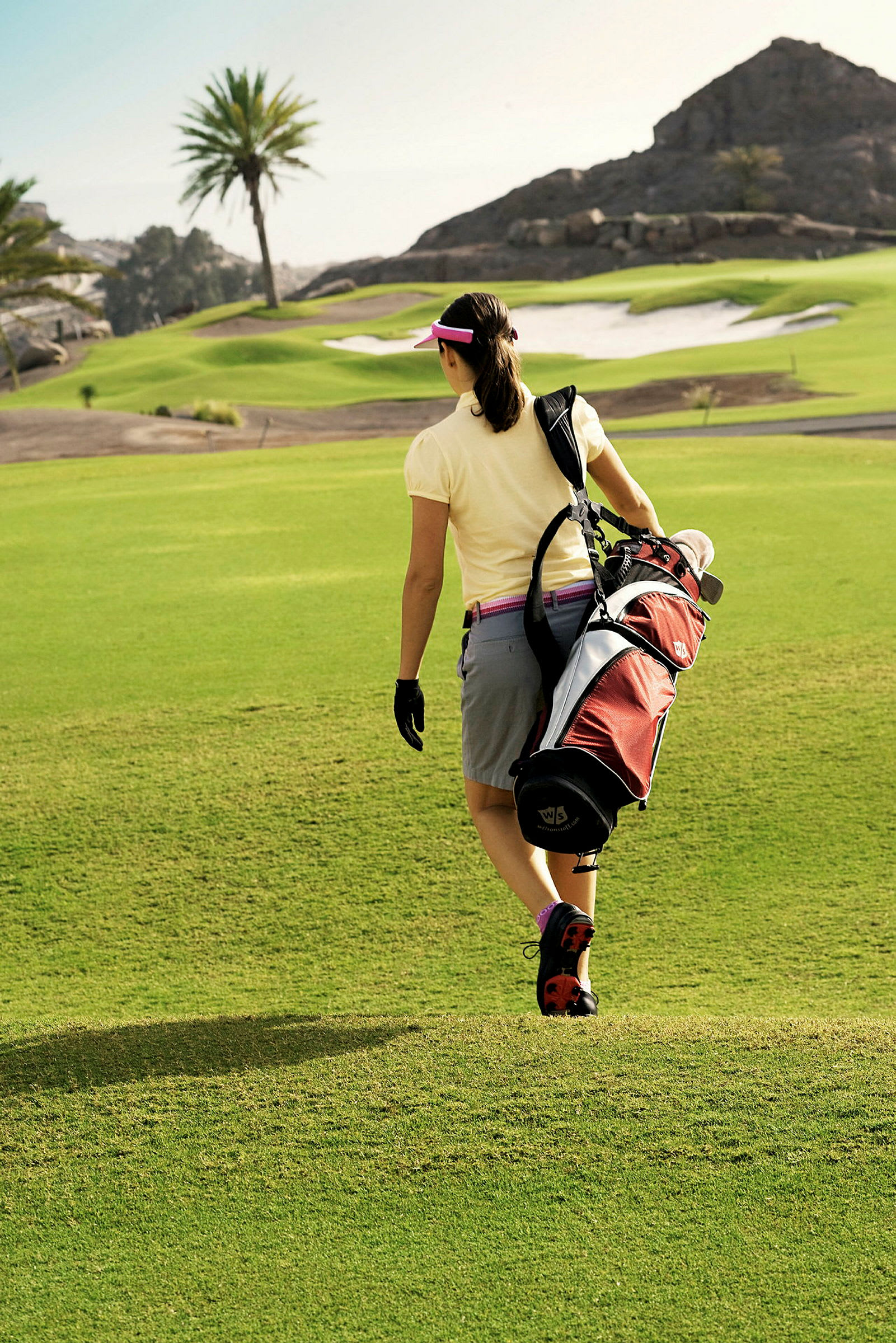 En person går på en golfbane med en golfbag på skuldra. (AI-generert tekst)