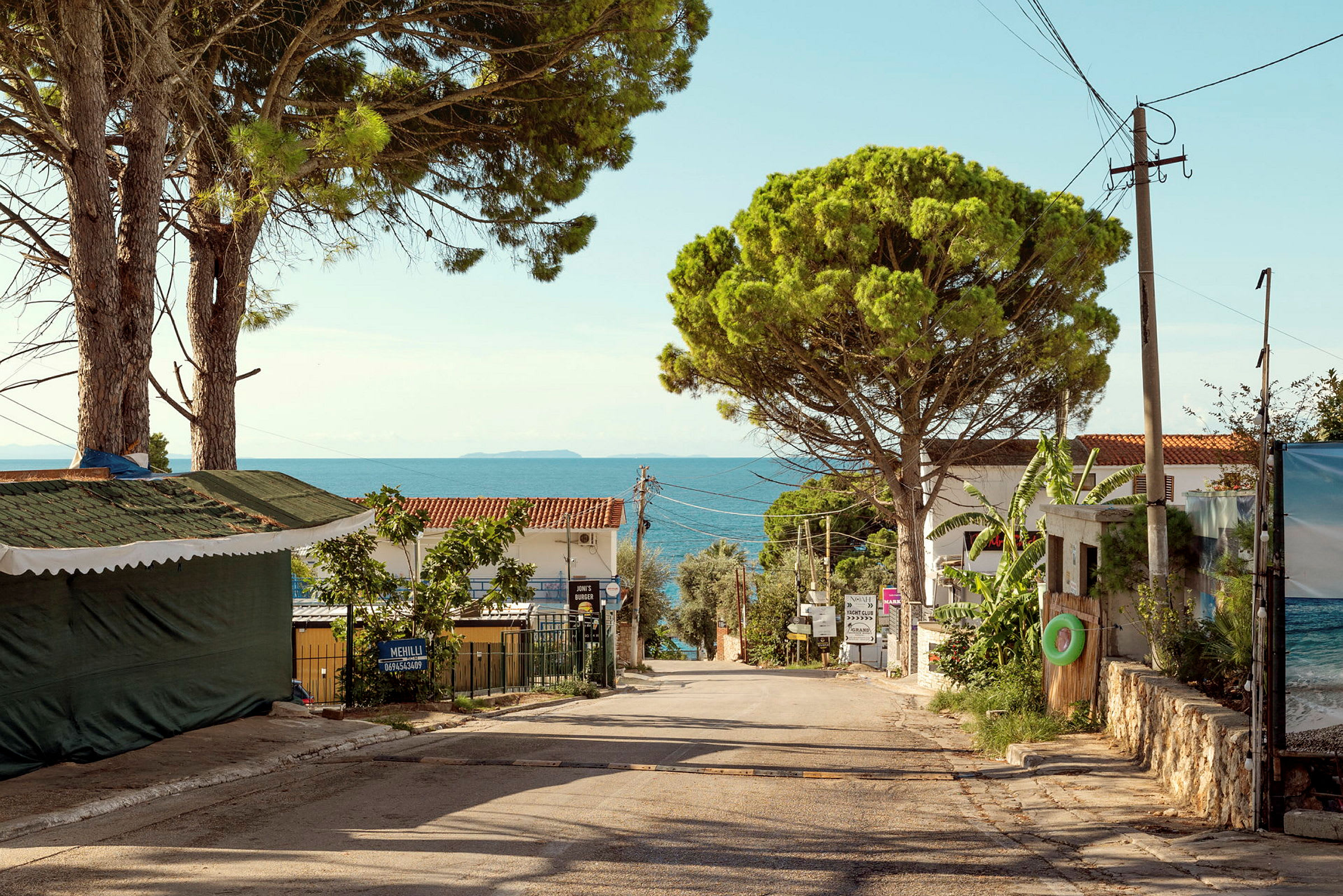 En rolig landevei med hus, trær og havet i bakgrunnen. (AI-generert tekst)