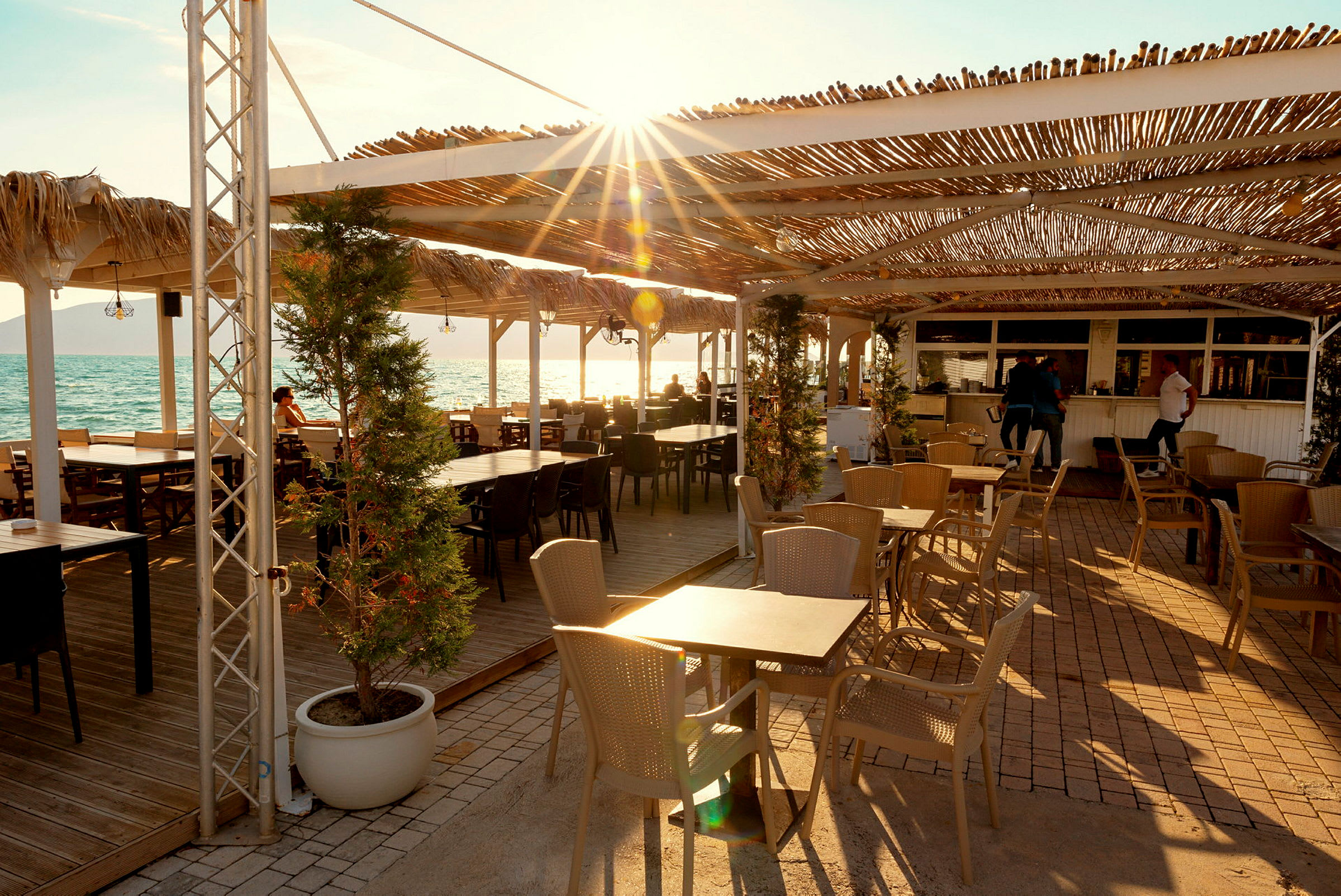Strandnær restaurant med tak og uteservering. (AI-generert tekst)
