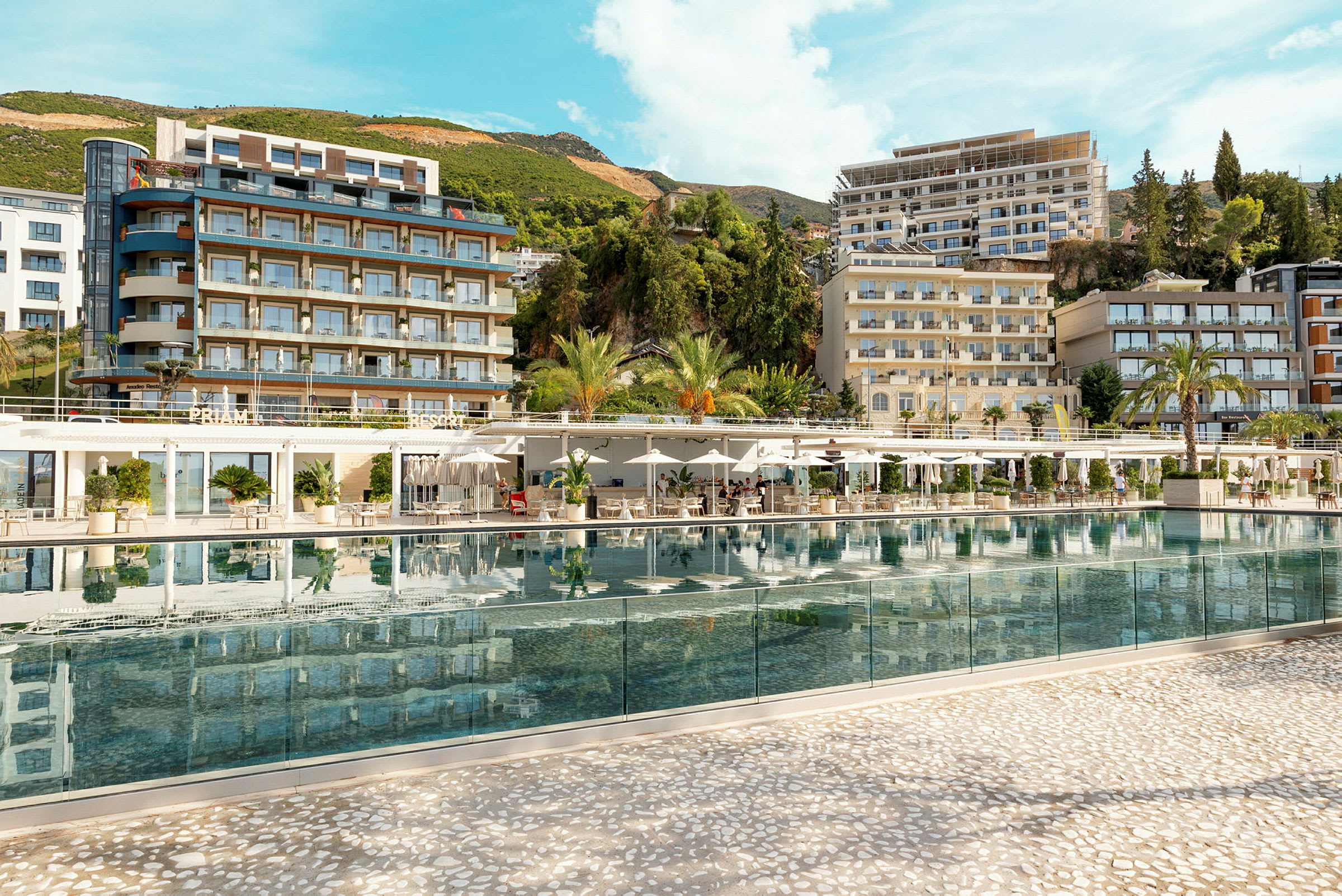 Hotellkompleks med basseng i fokus, omgitt av grøntområder og bygninger. (AI-generert tekst)