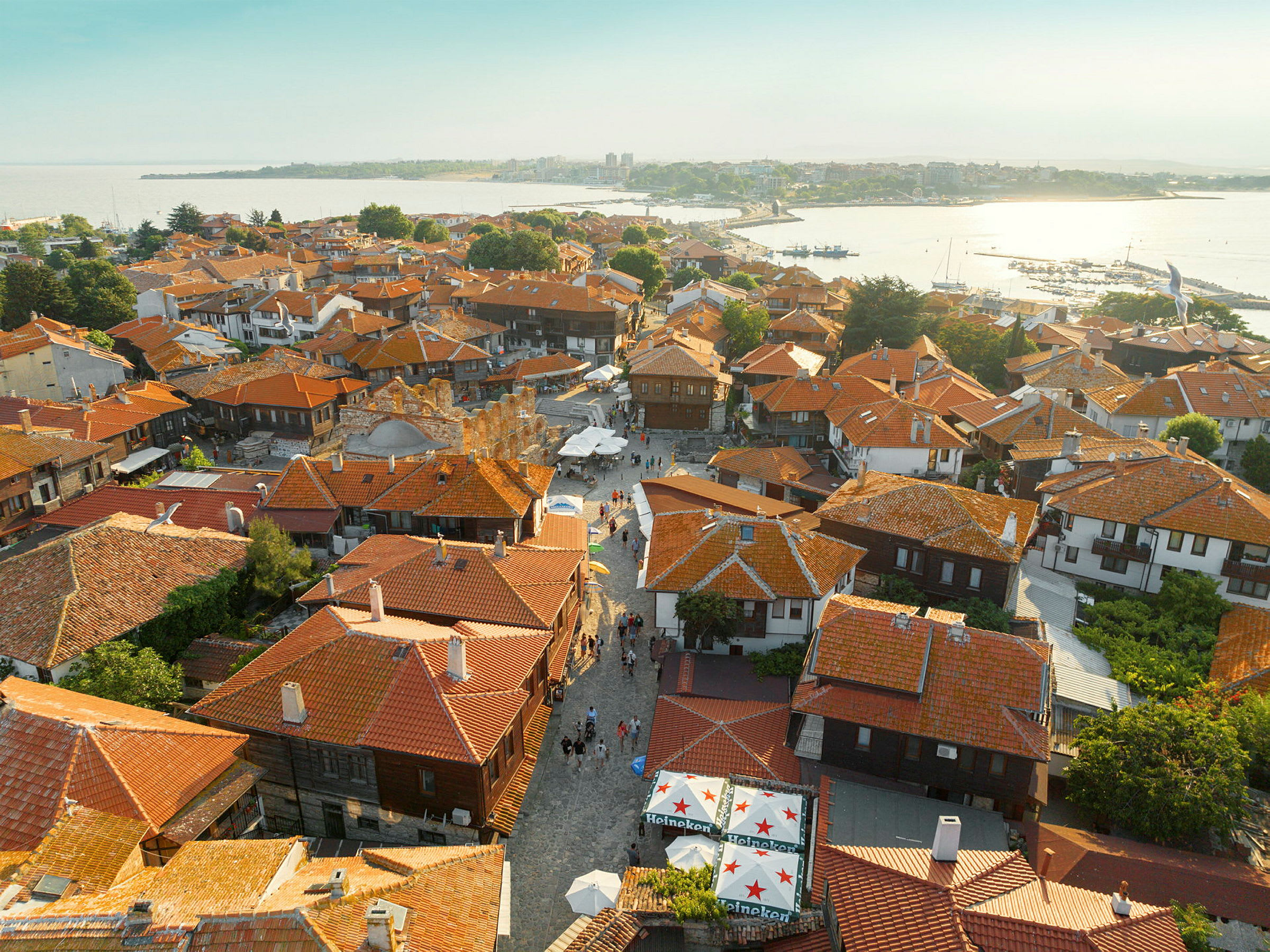 Luftfoto av en by med flere hus med røde tak, brosteinsgater og grønne trær. (AI-generert tekst)