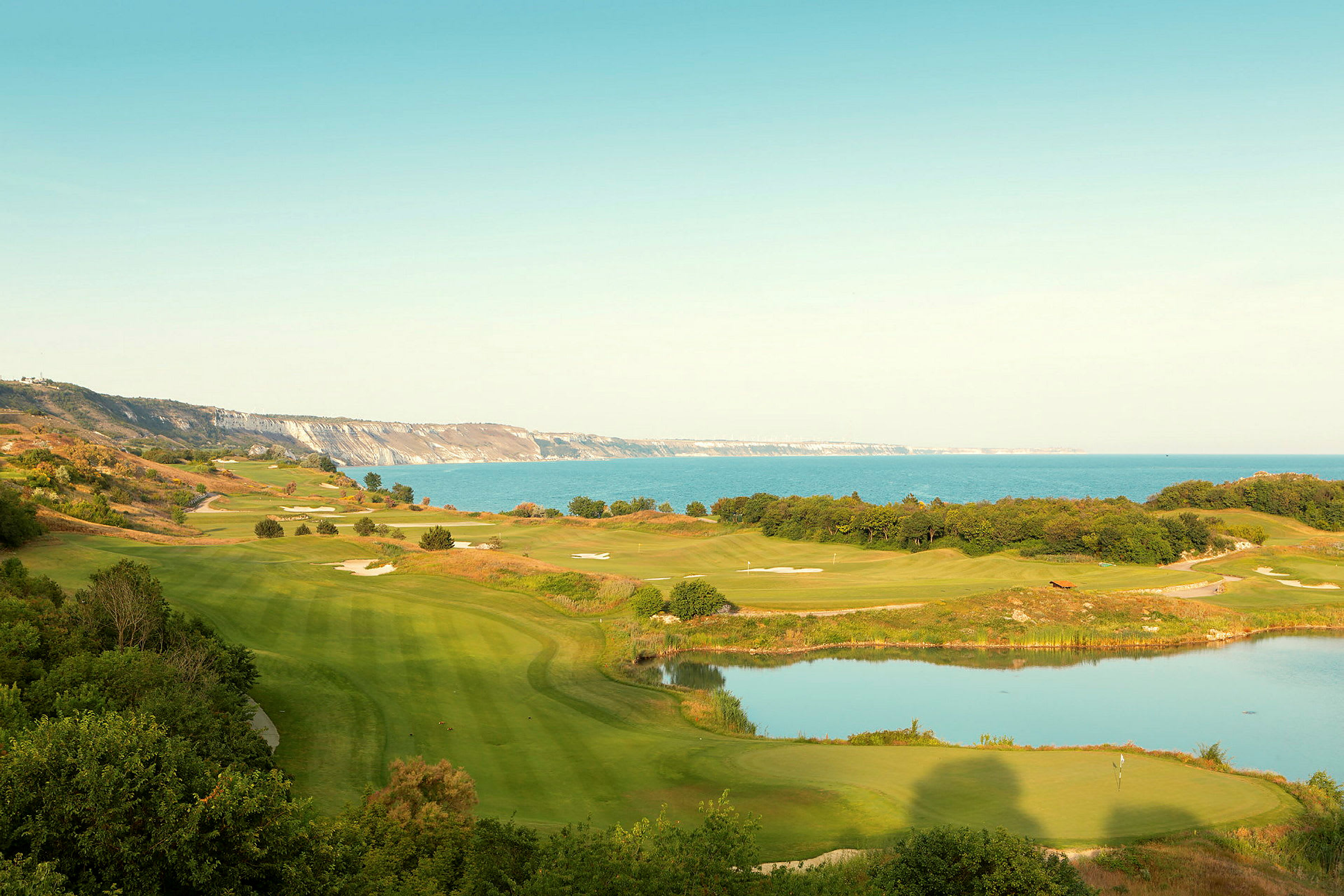 Utsikt over en golfbane med nærliggende innsjø og kystlinje. (AI-generert tekst)