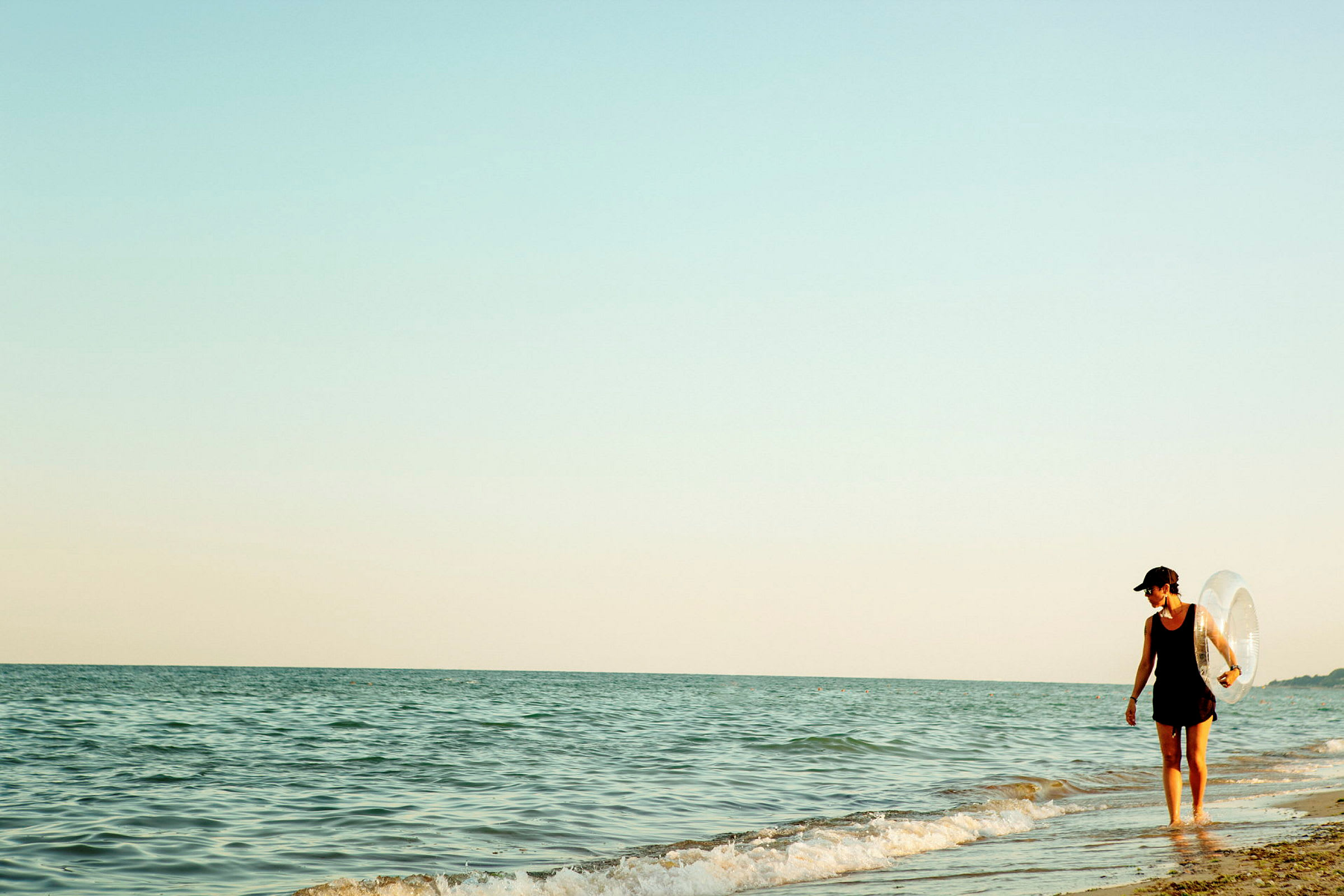 Person går langs strandkanten ved havet. (AI-generert tekst)