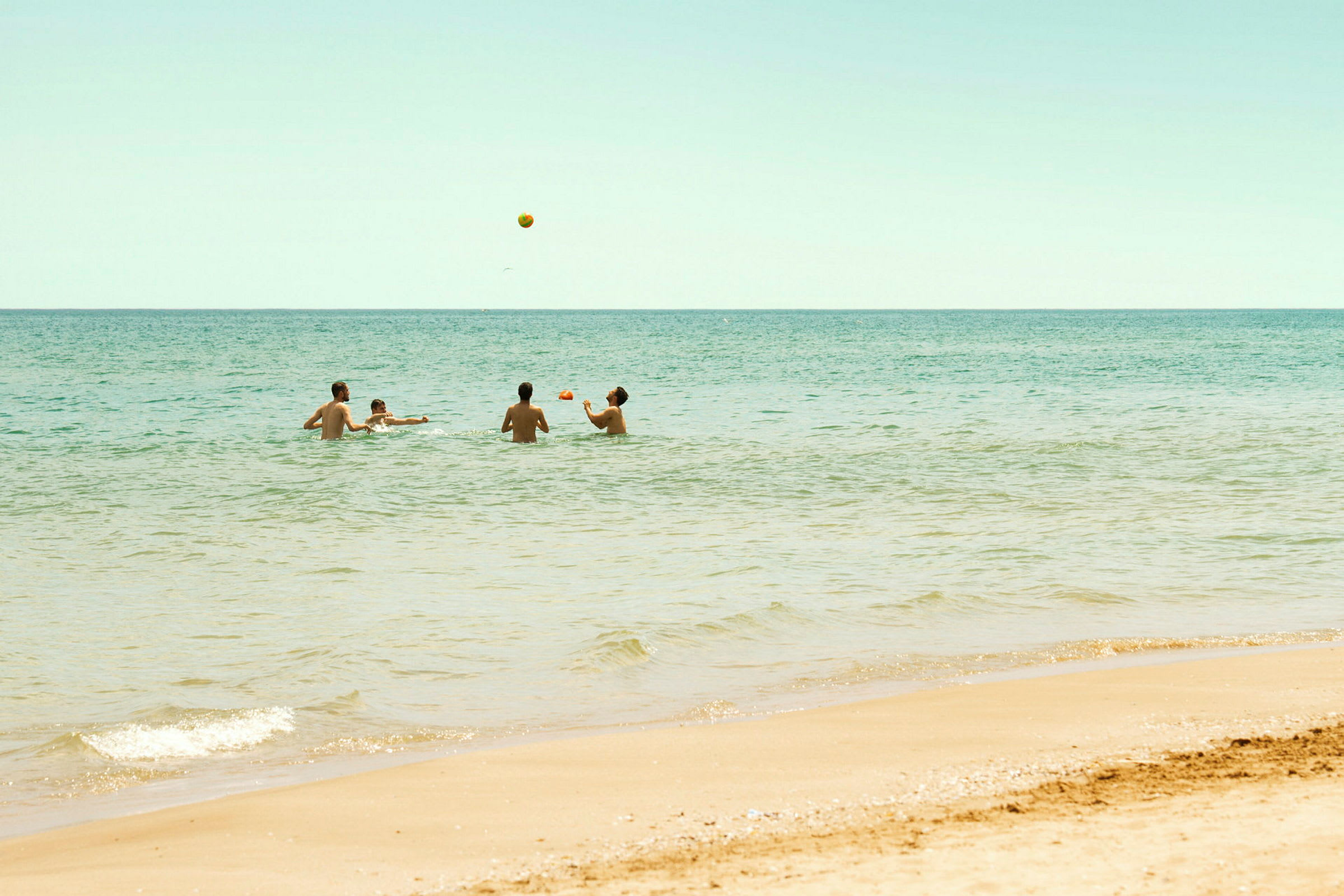 Personer som spiller med en ball i havet nær en sandstrand. (AI-generert tekst)