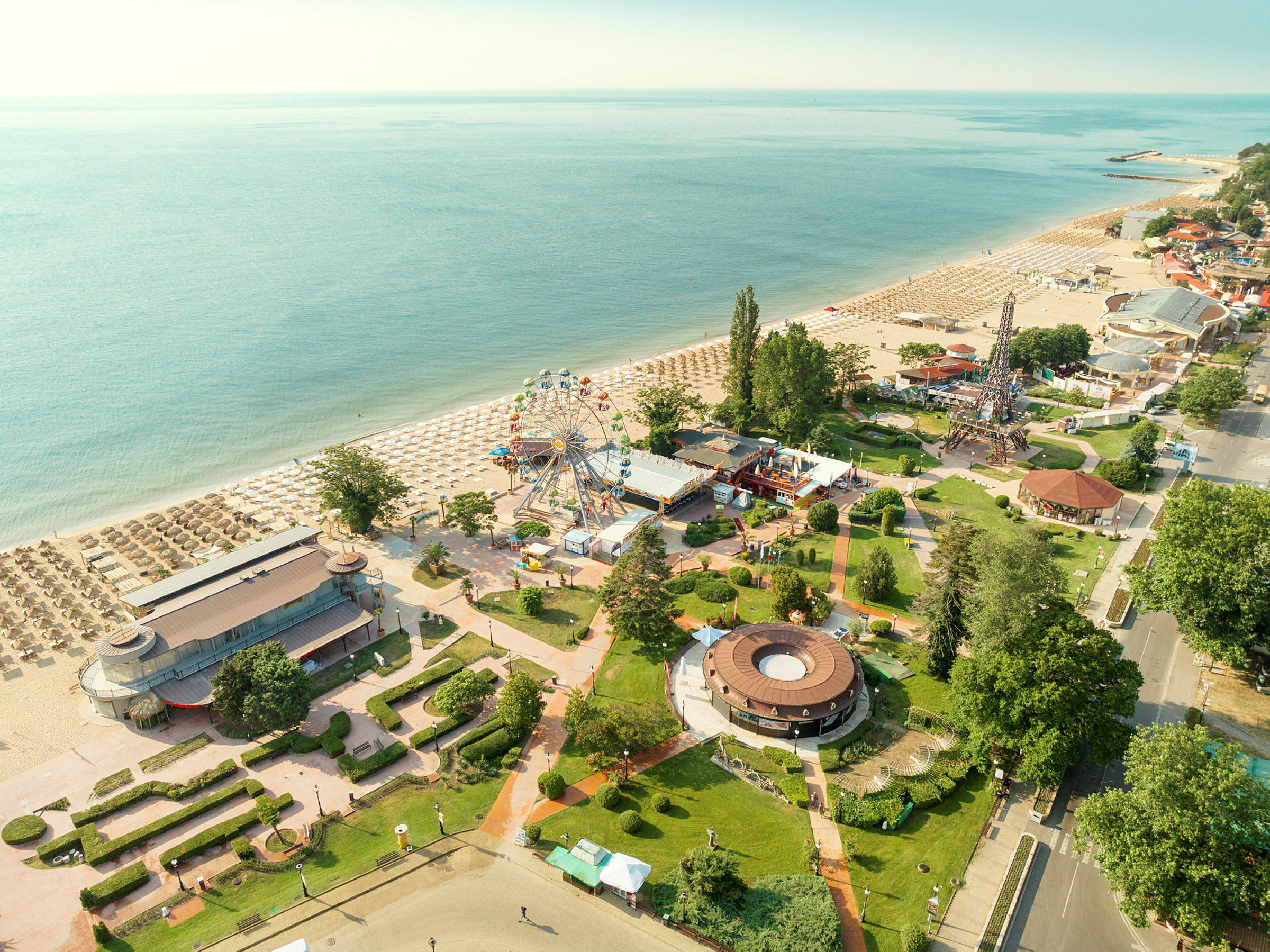 Strand med solsenger, fornøyelsesområde og grøntområder. (AI-generert tekst)