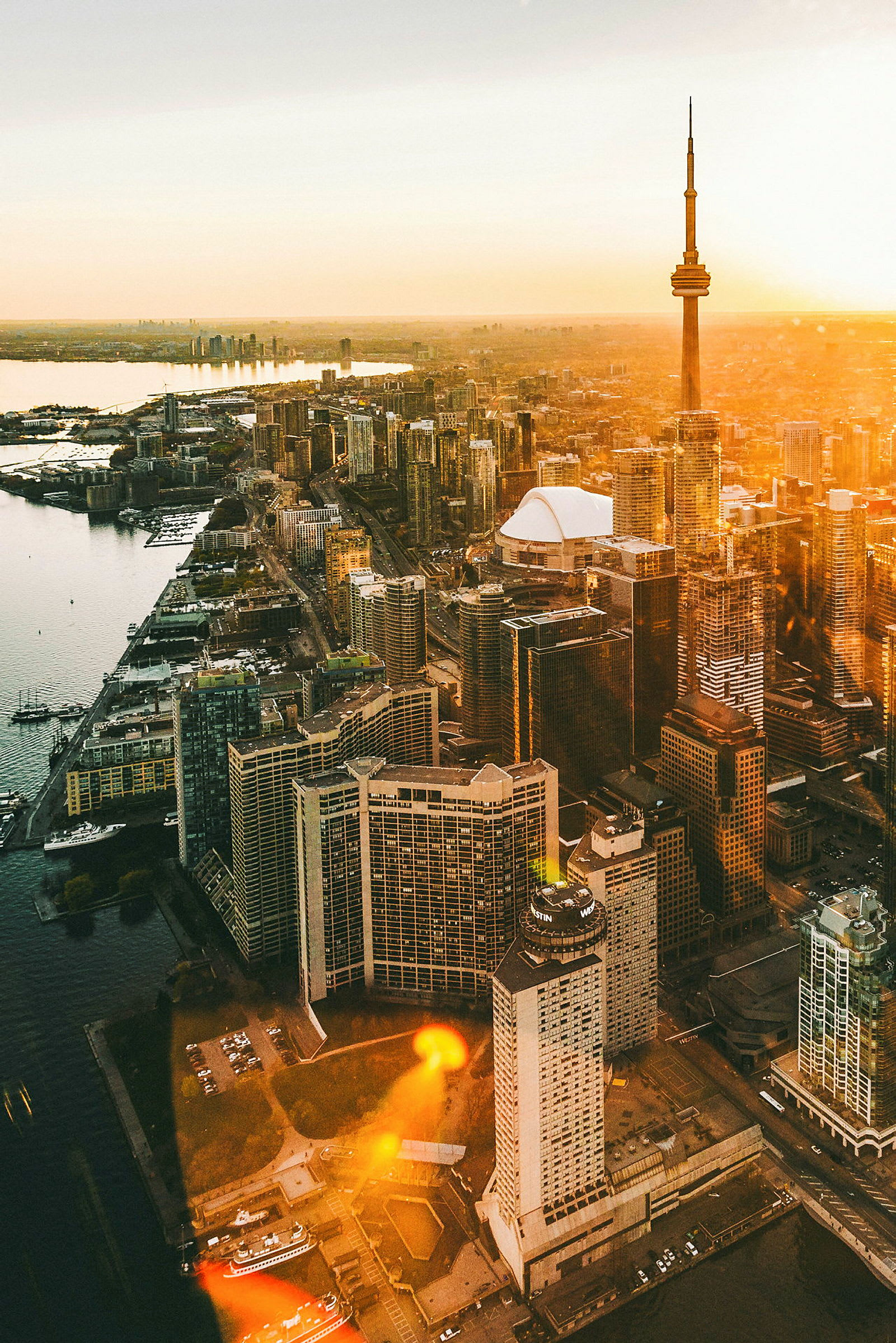 Bildet viser utsikt over Toronto med CN Tower ved solnedgang. (AI-generert tekst)