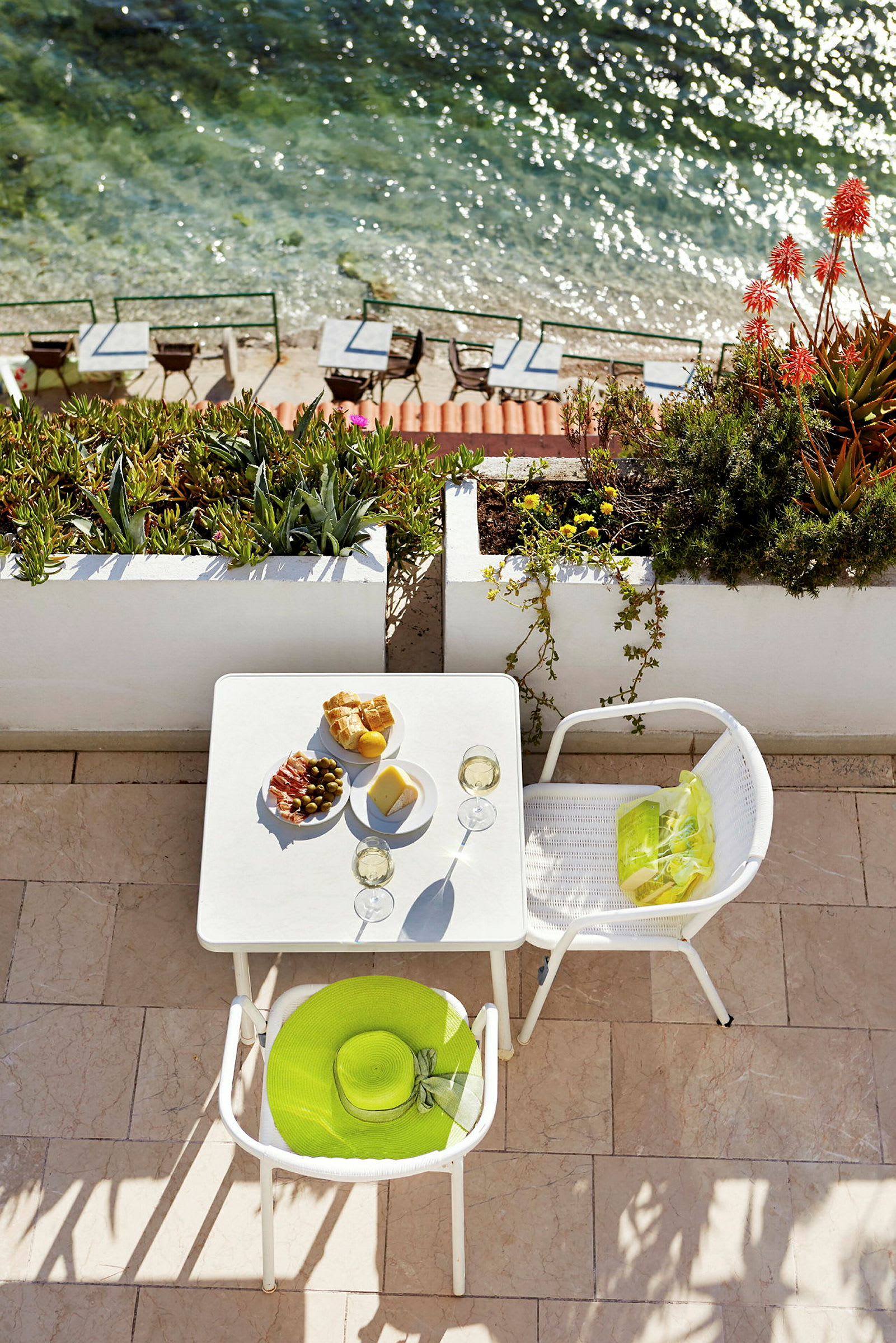 Bord med mat og drikke på terrasse ved havet. (AI-generert tekst)