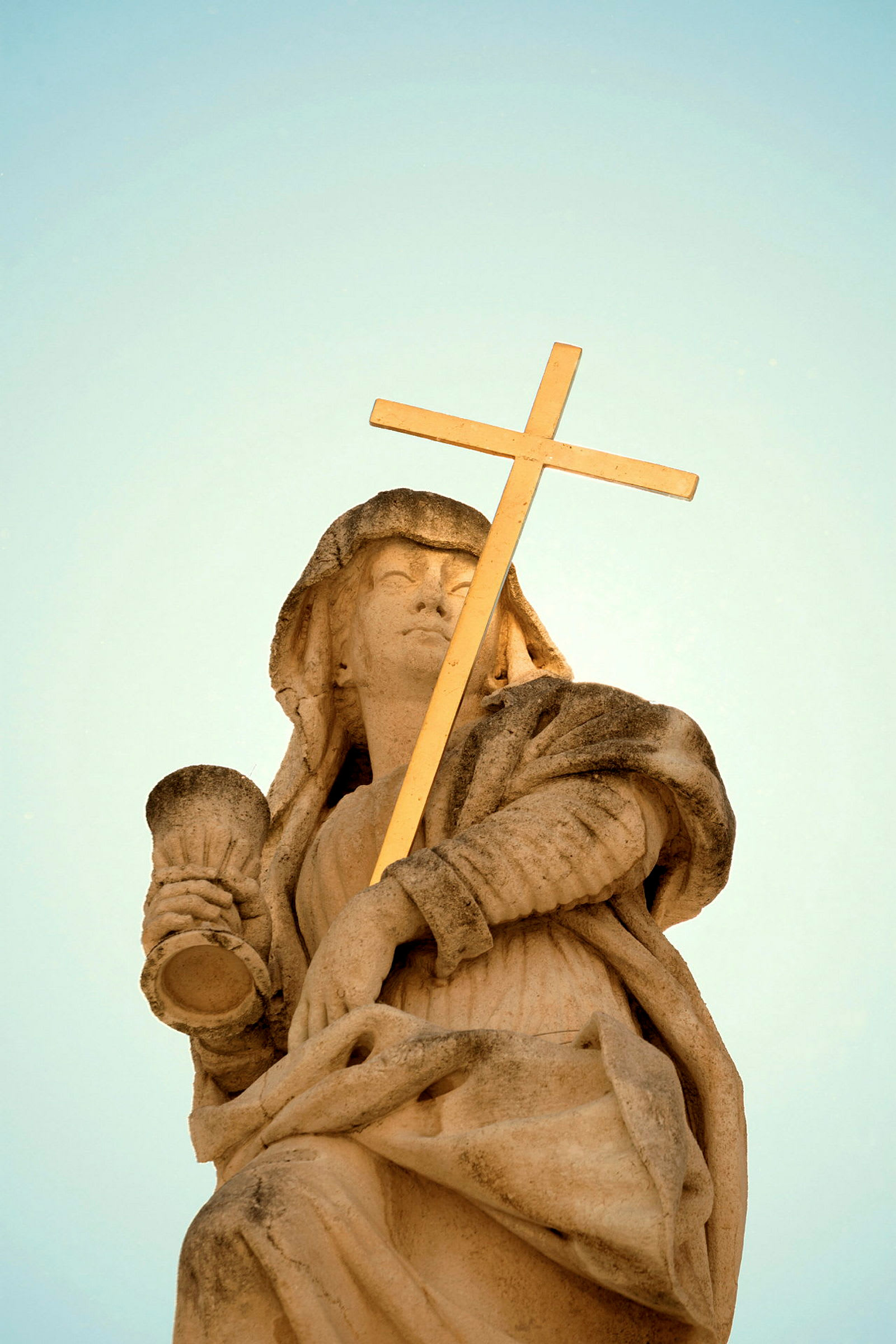 Statue av en person med et gullkors og beger. (AI-generert tekst)
