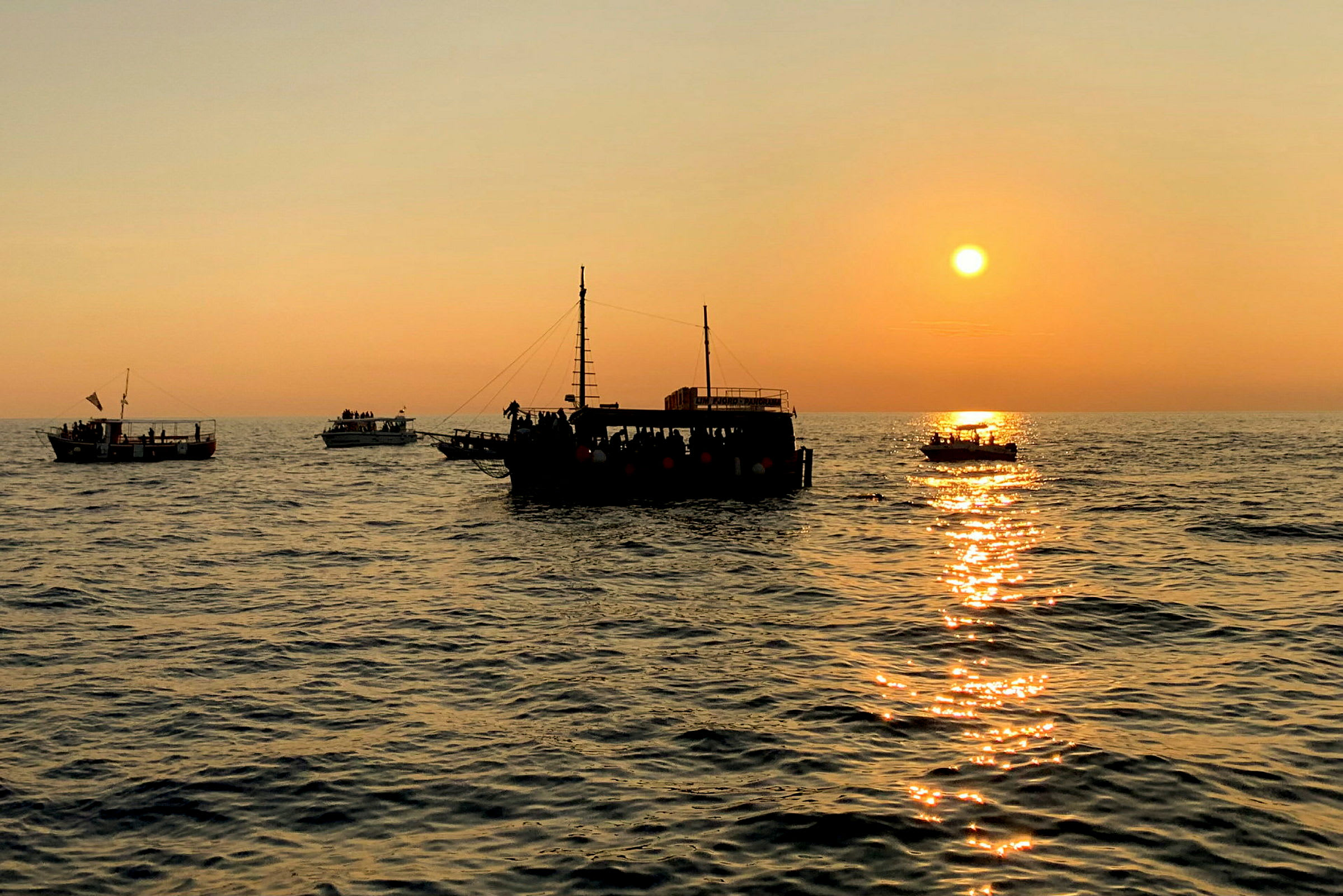 Flere båter på havet ved solnedgang. (AI-generert tekst)