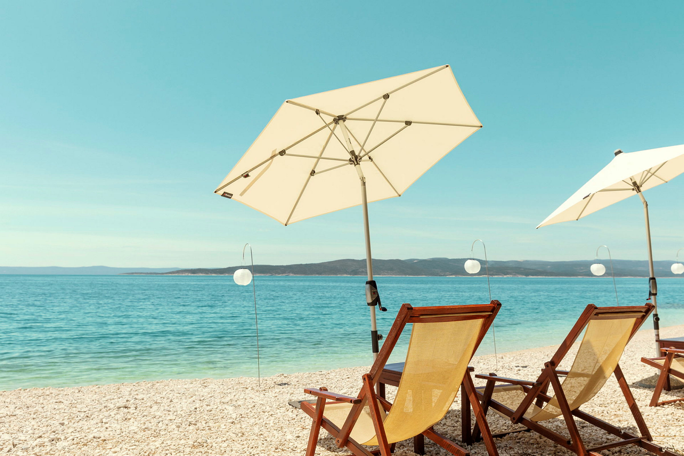 Solstoler og parasoller på stranden med havet i bakgrunnen. (AI-generert tekst)