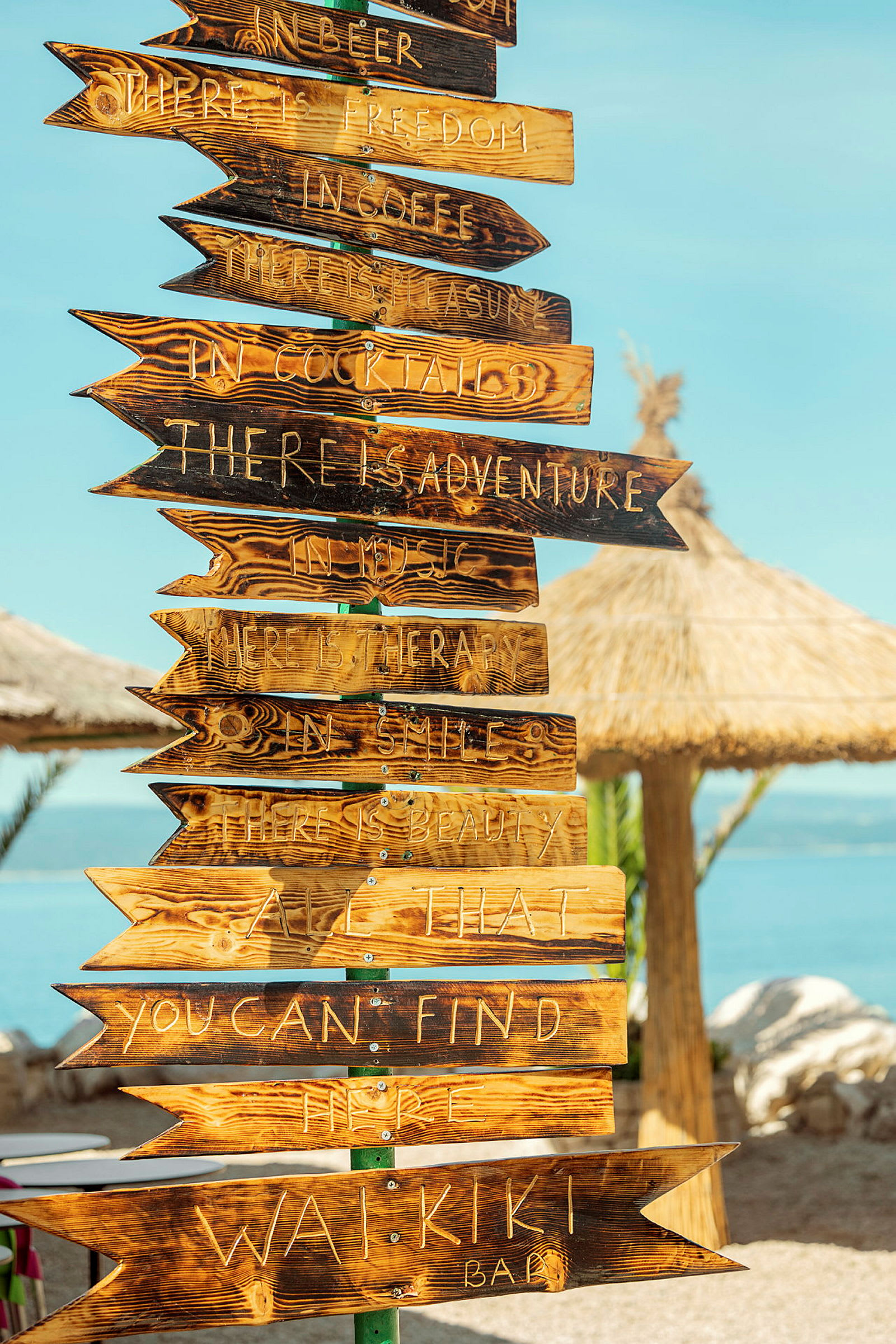 Treviser med inngravert tekst som fungerer som skilt ved en strandbar. (AI-generert tekst)