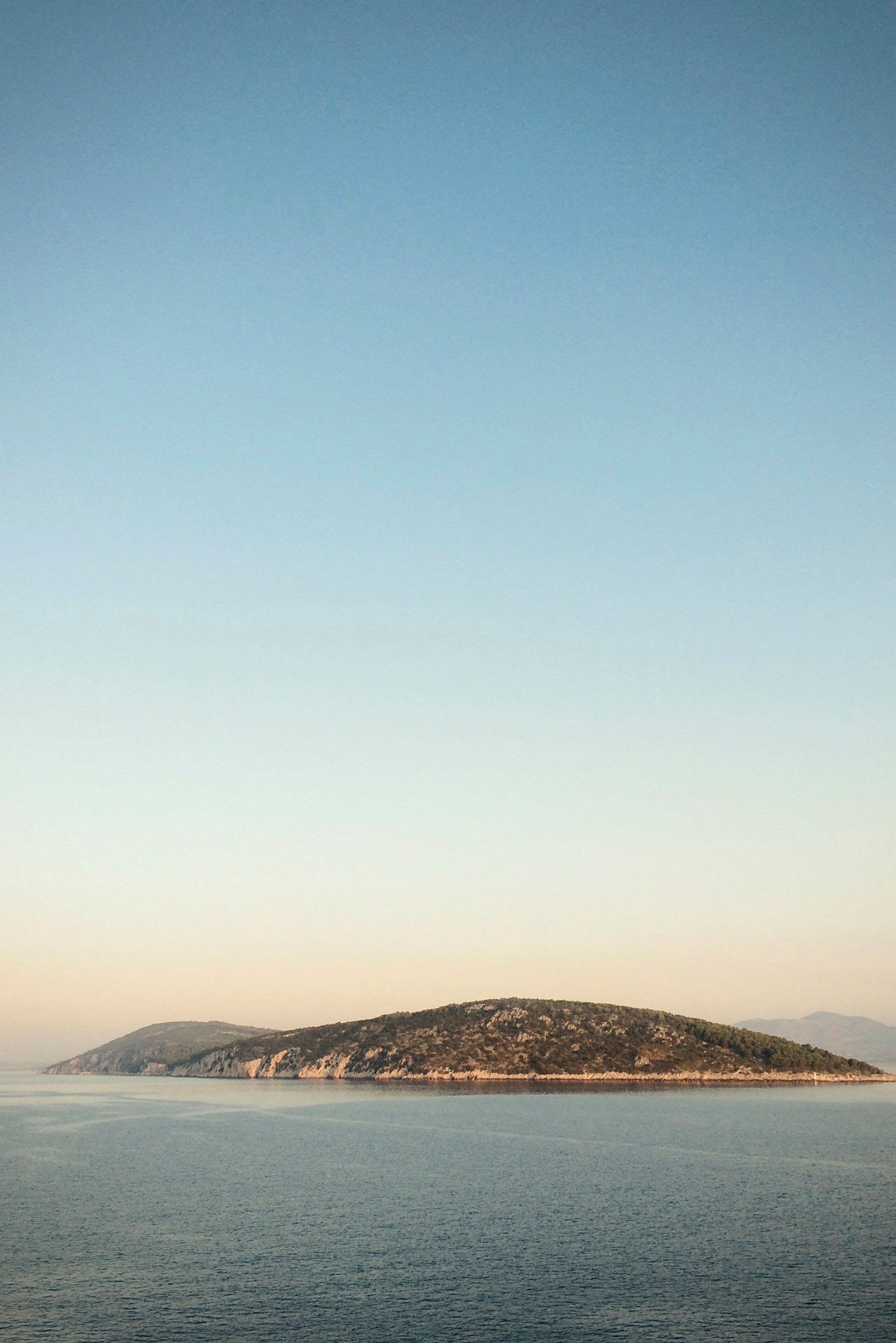 En liten øy i havet under en klar himmel. (AI-generert tekst)