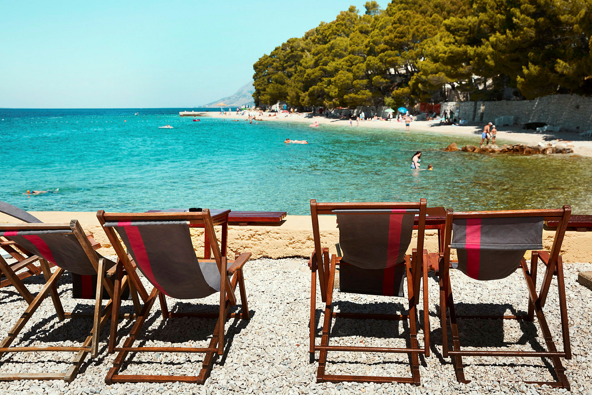 Solstoler ved en strand med klart vann. (AI-generert tekst)