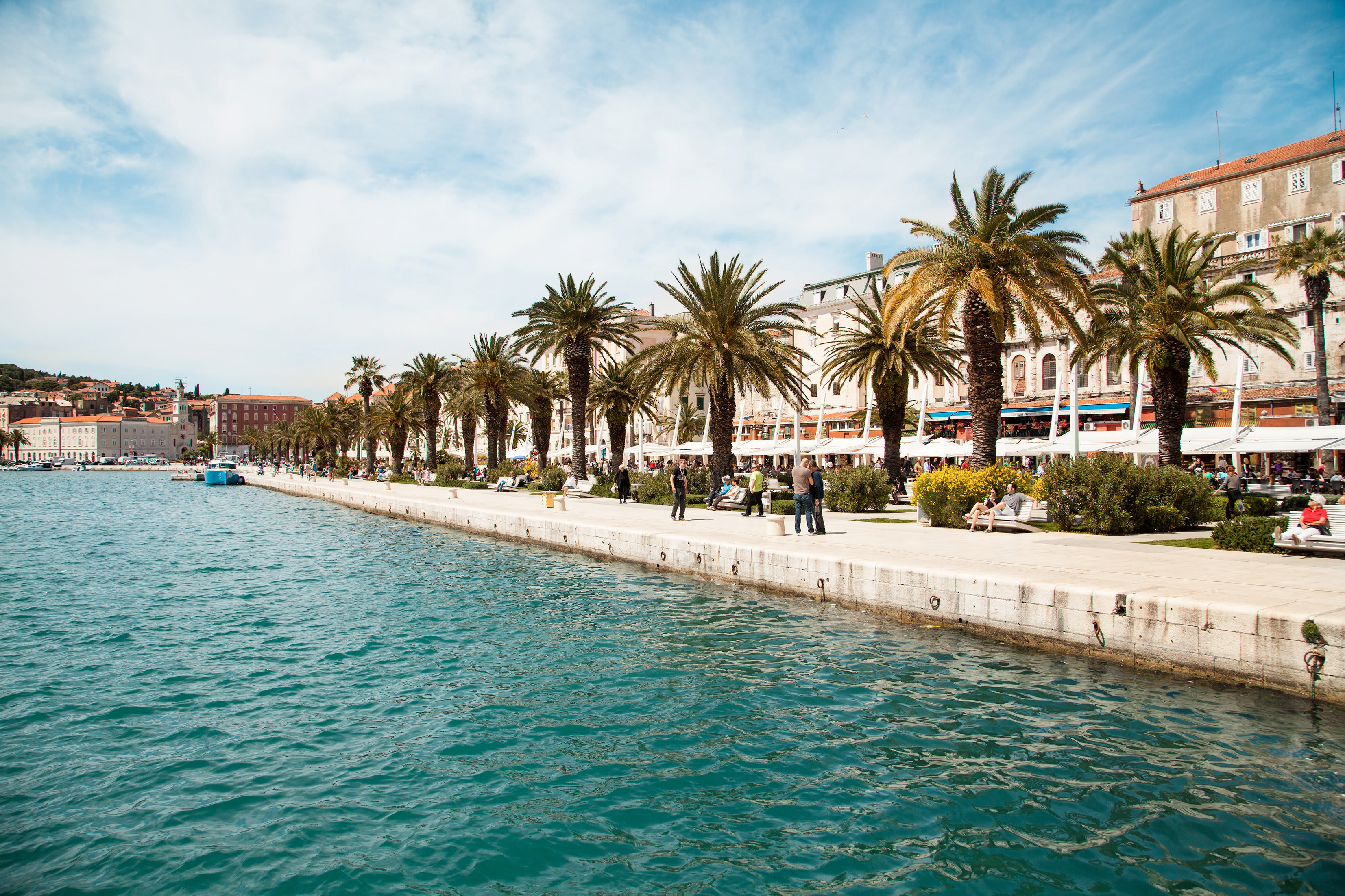 En havnepromenade med palmer ved vannet. (AI-generert tekst)