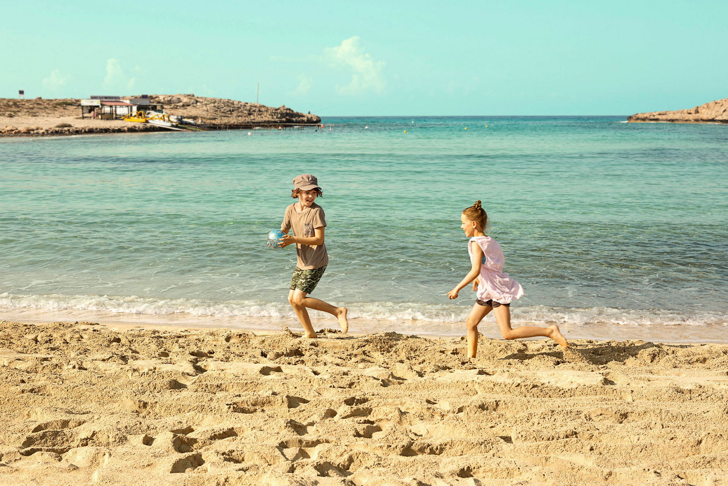 To barn leker på stranden ved havet. (AI-generert tekst)
