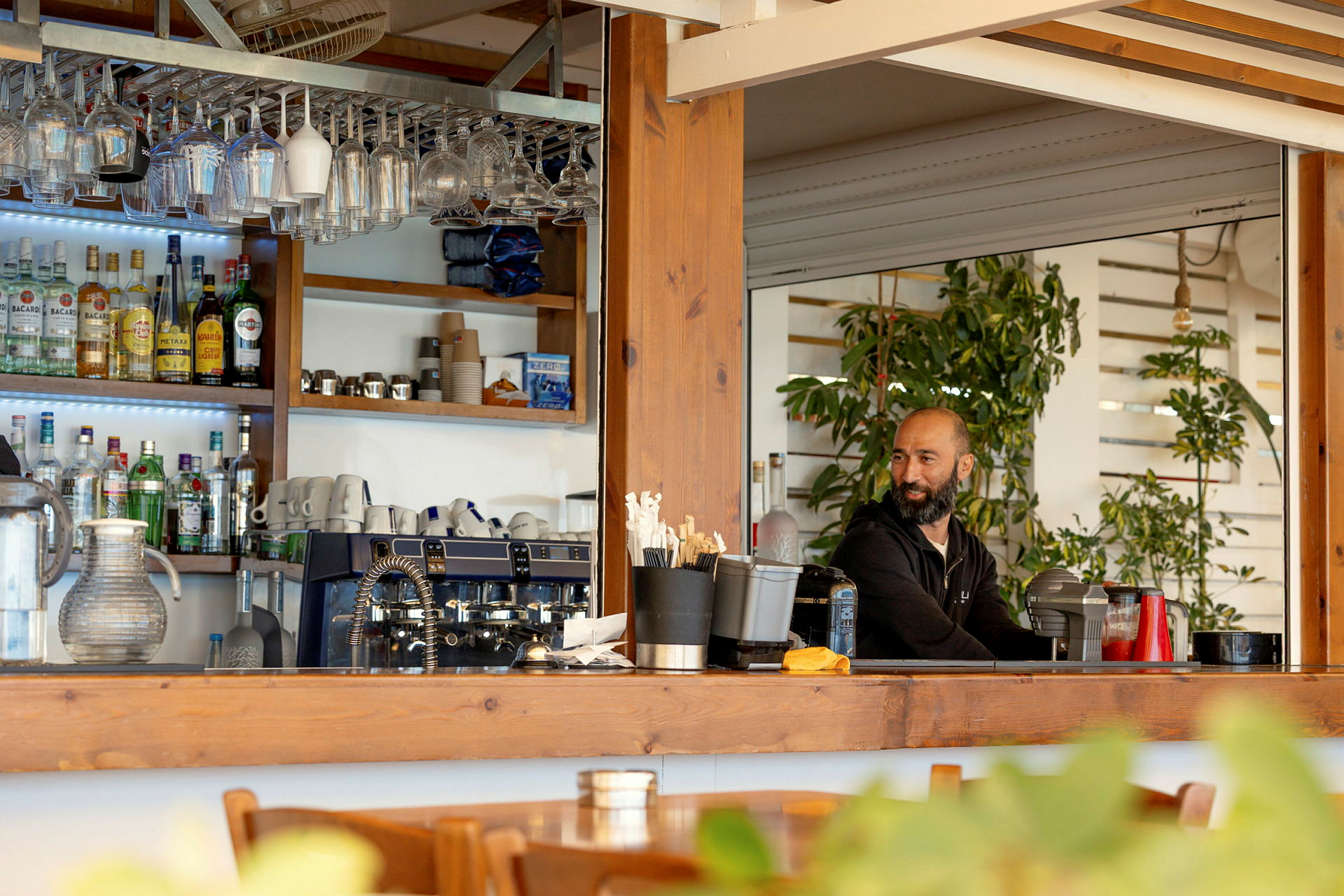 En bar med hyller for drikke, glass og kaffemaskiner. (AI-generert tekst)