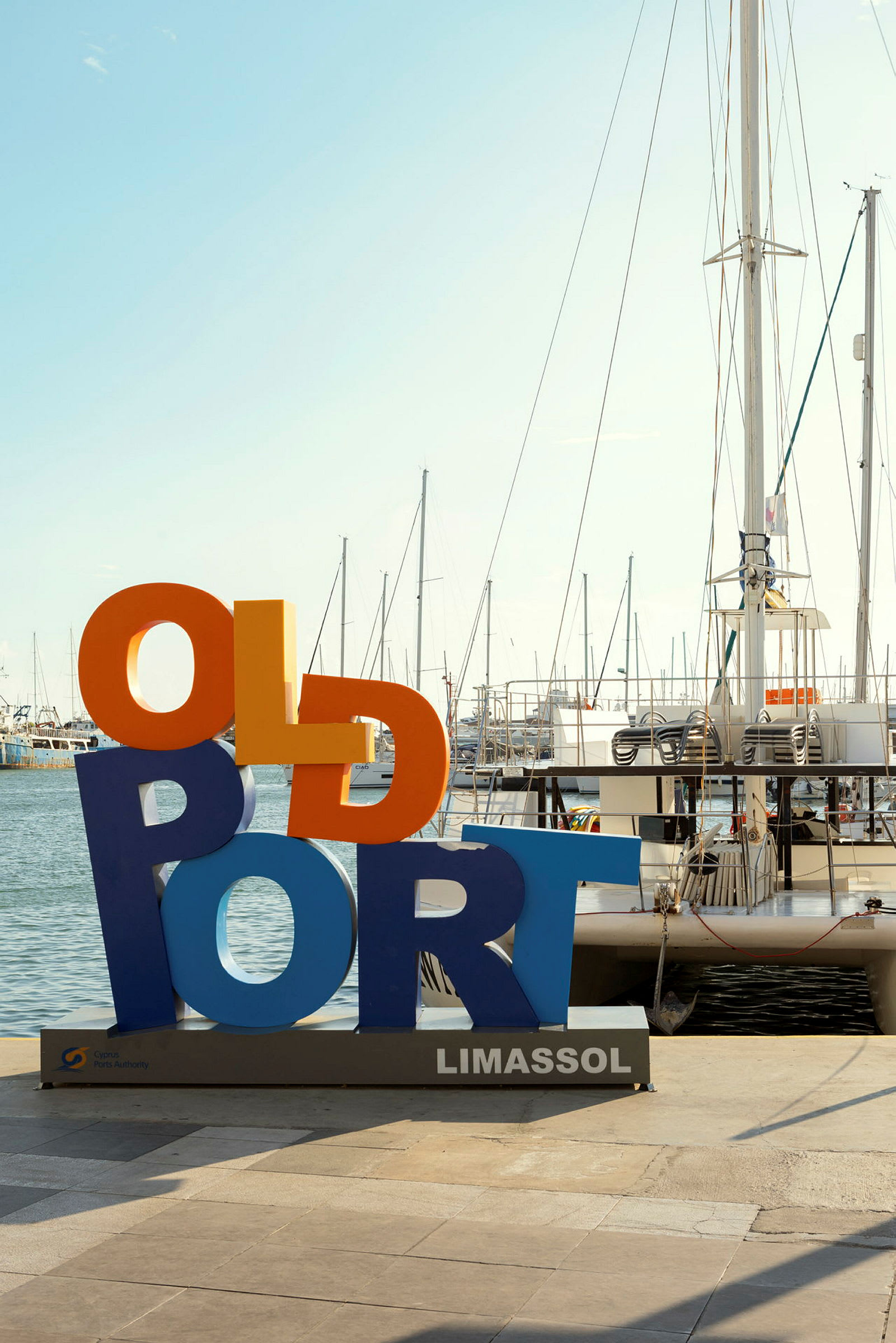 Fargerik skilt med teksten 'Old Port' ved havnen i Limassol, seilbåter i bakgrunnen. (AI-generert tekst)