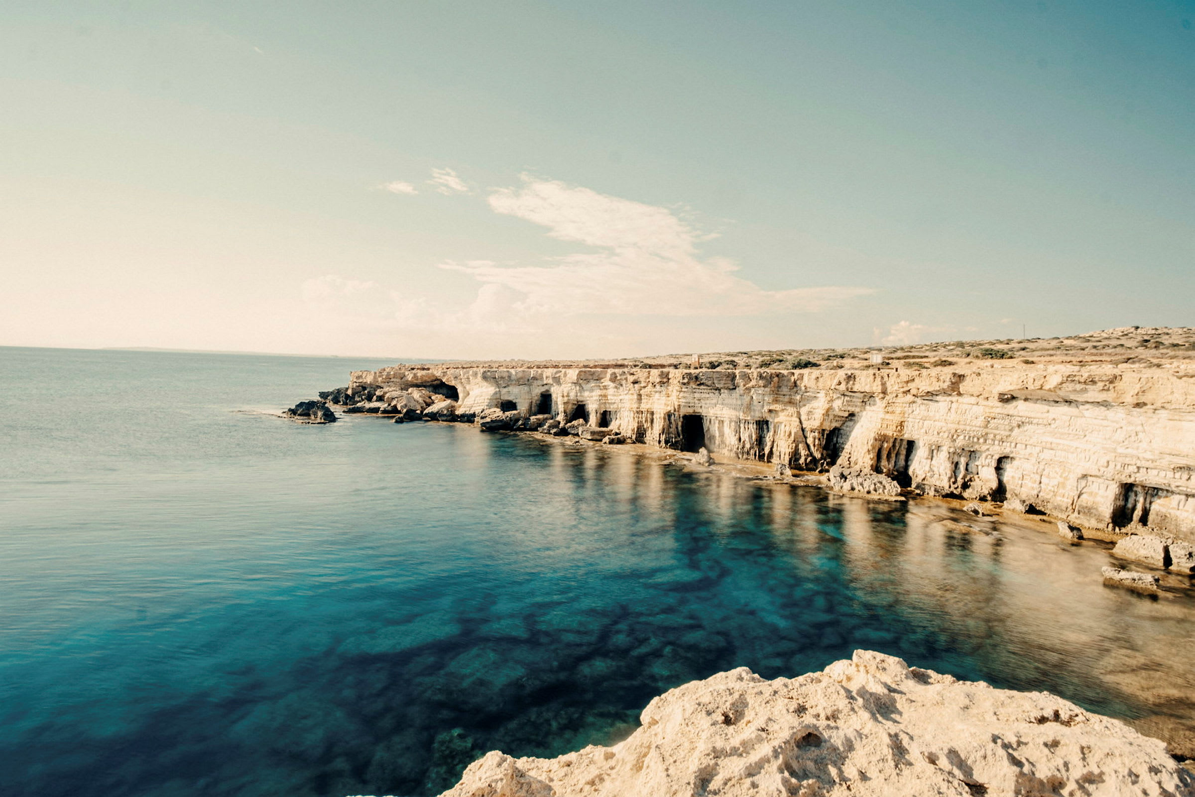 Bilde av en klipperik kystlinje ved havet under en klar himmel. (AI-generert tekst)