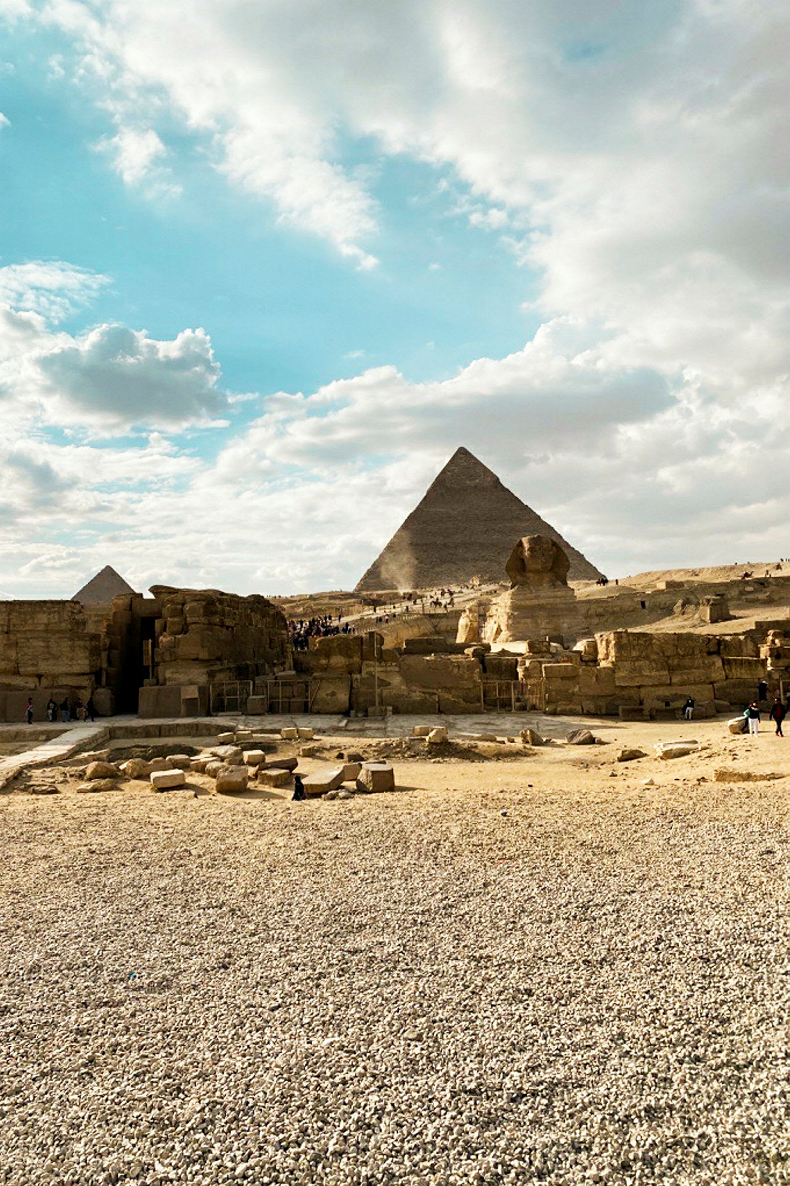 Steinete område med pyramider og sfinksen under en klar himmel. (AI-generert tekst)