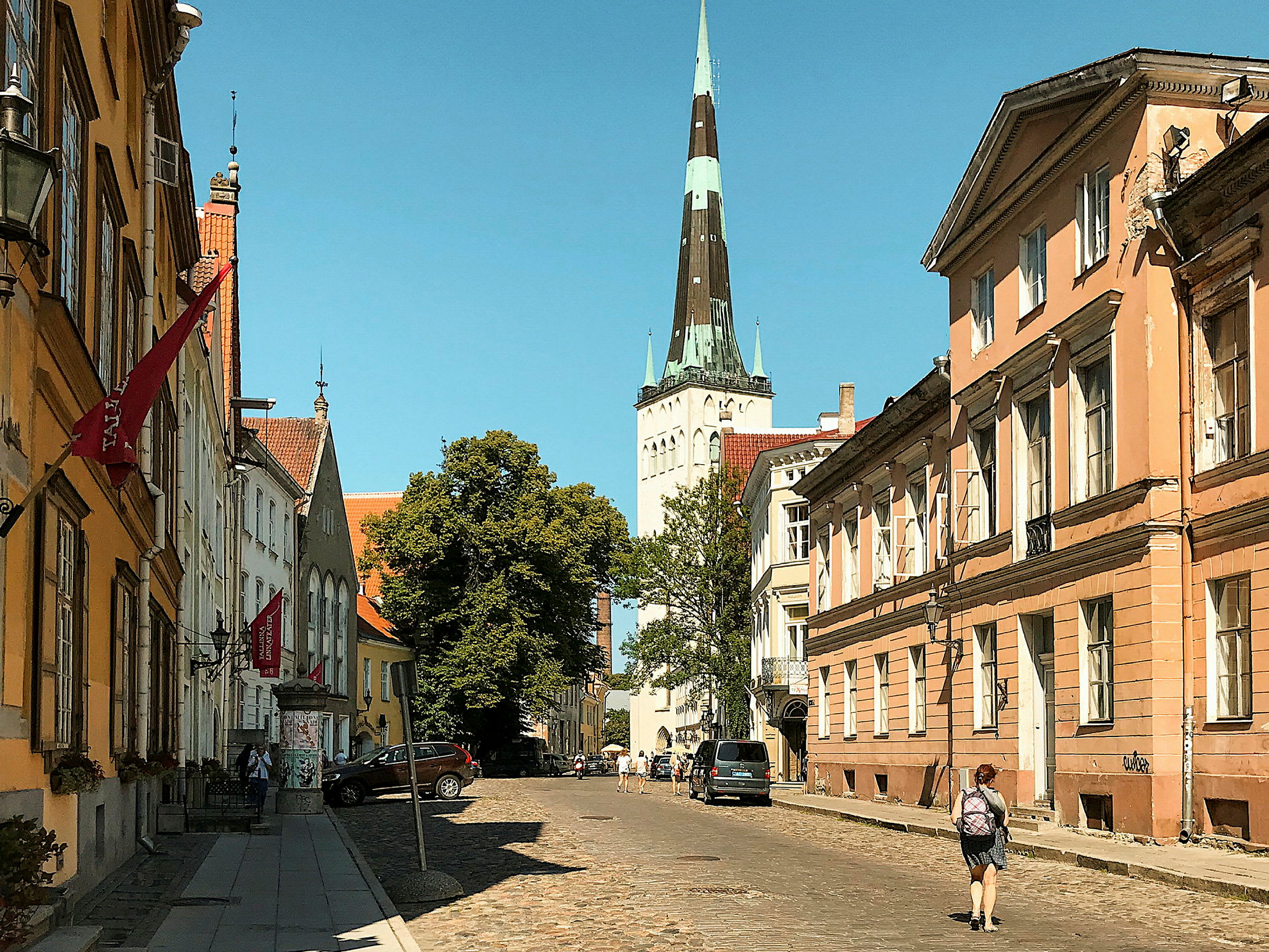 En bygateg med gamle bygninger og et kirketårn i bakgrunnen. (AI-generert tekst)