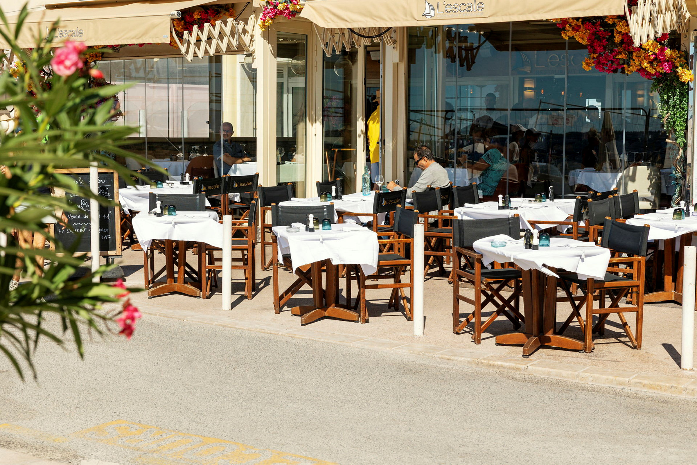 Uteservering ved en restaurant med bord og stoler under en markise. (AI-generert tekst)