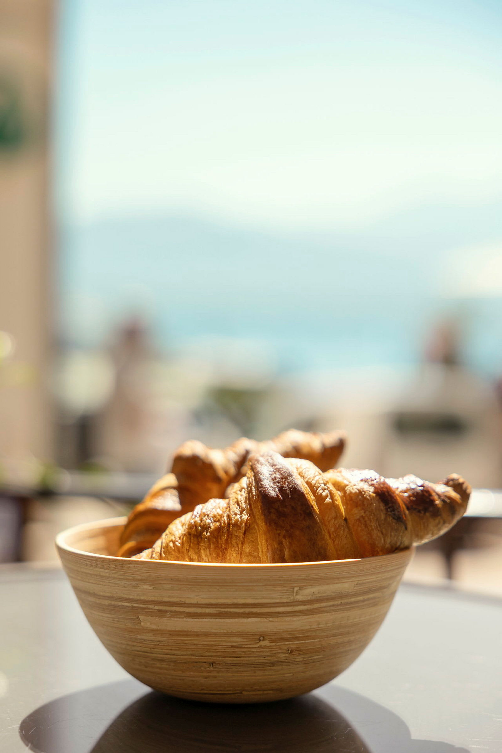 En bolle med croissanter står på et bord med uskarp bakgrunn. (AI-generert tekst)