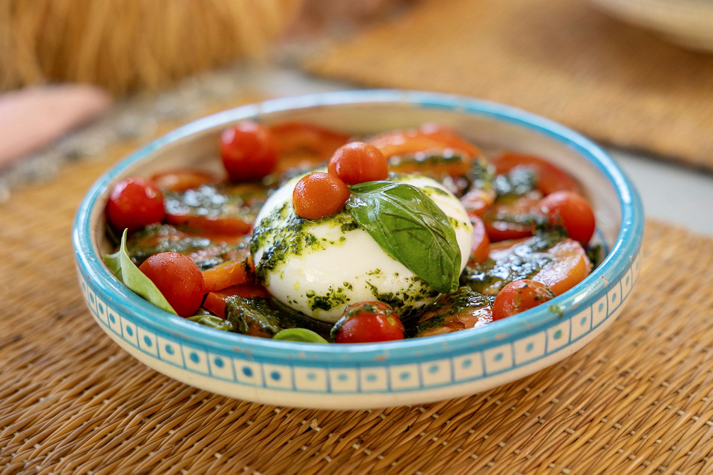 En tallerken med burrata, cherrytomater, fersk basilikum og pesto. (AI-generert tekst)