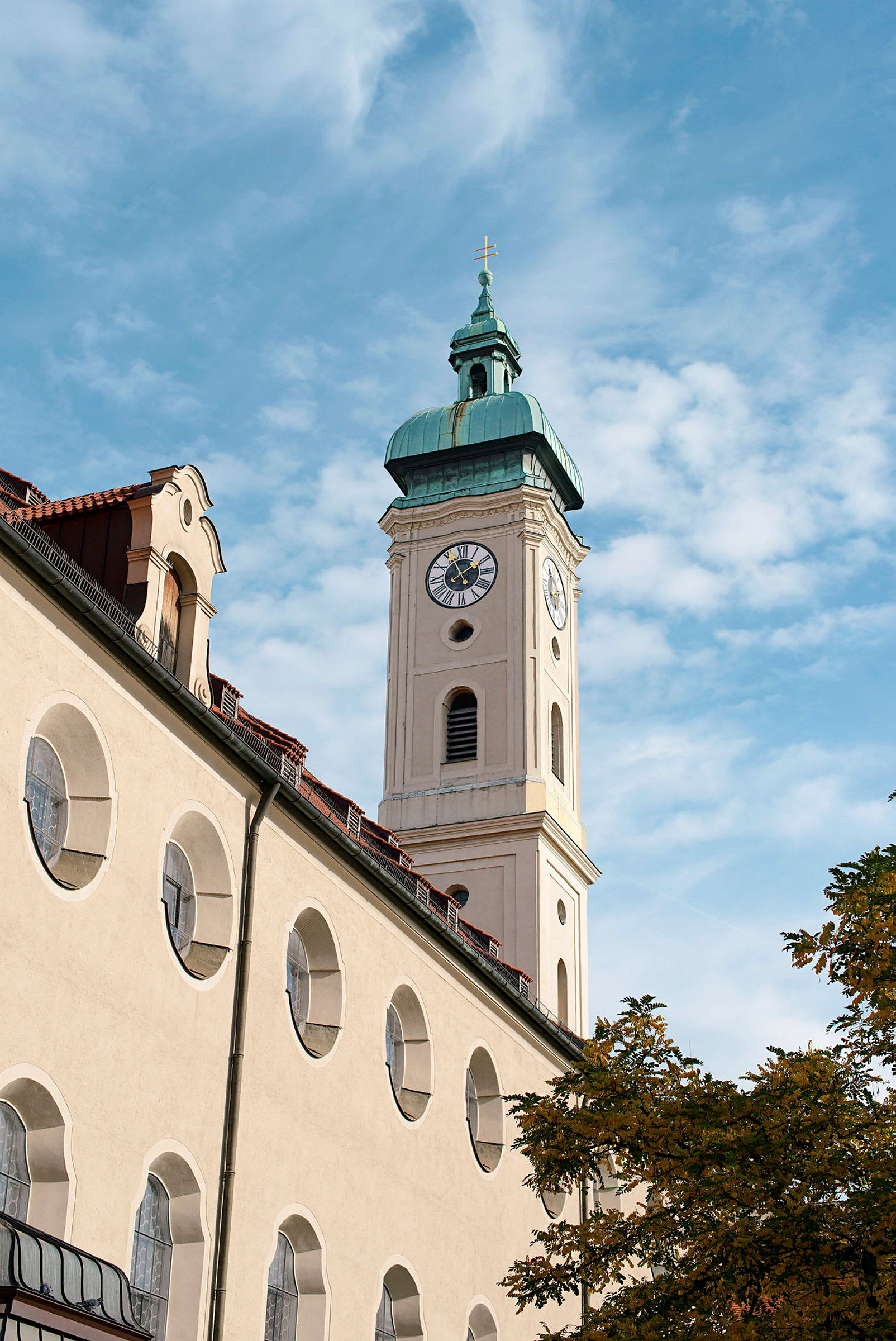 En kirke med et klokketårn og en spir med et kors på toppen, mot en blå himmel. (AI-generert tekst)