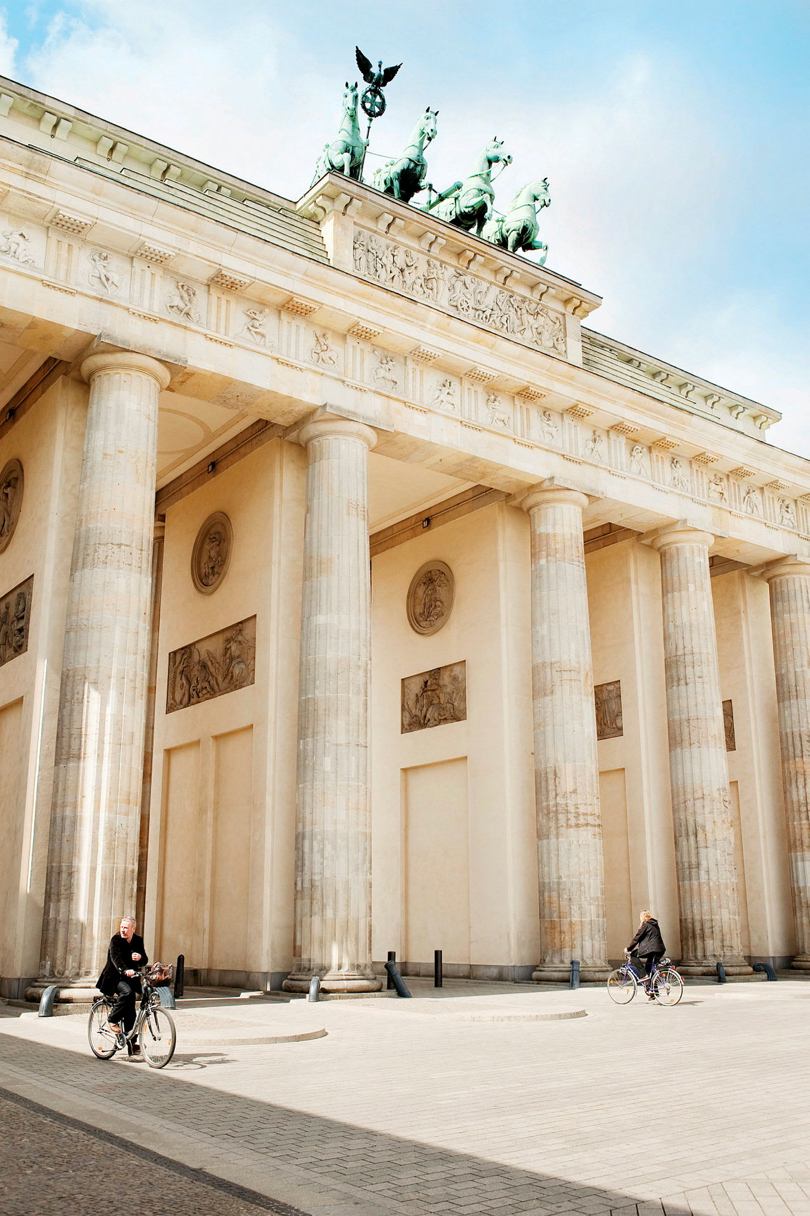 Brandenburger Tor med to syklister foran. (AI-generert tekst)