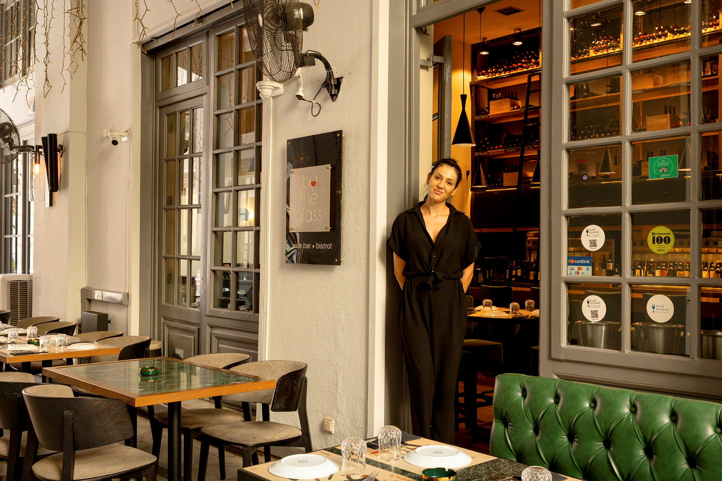 En restaurant med utendørsbord og glassdører som fører inn til en vinbar. (AI-generert tekst)