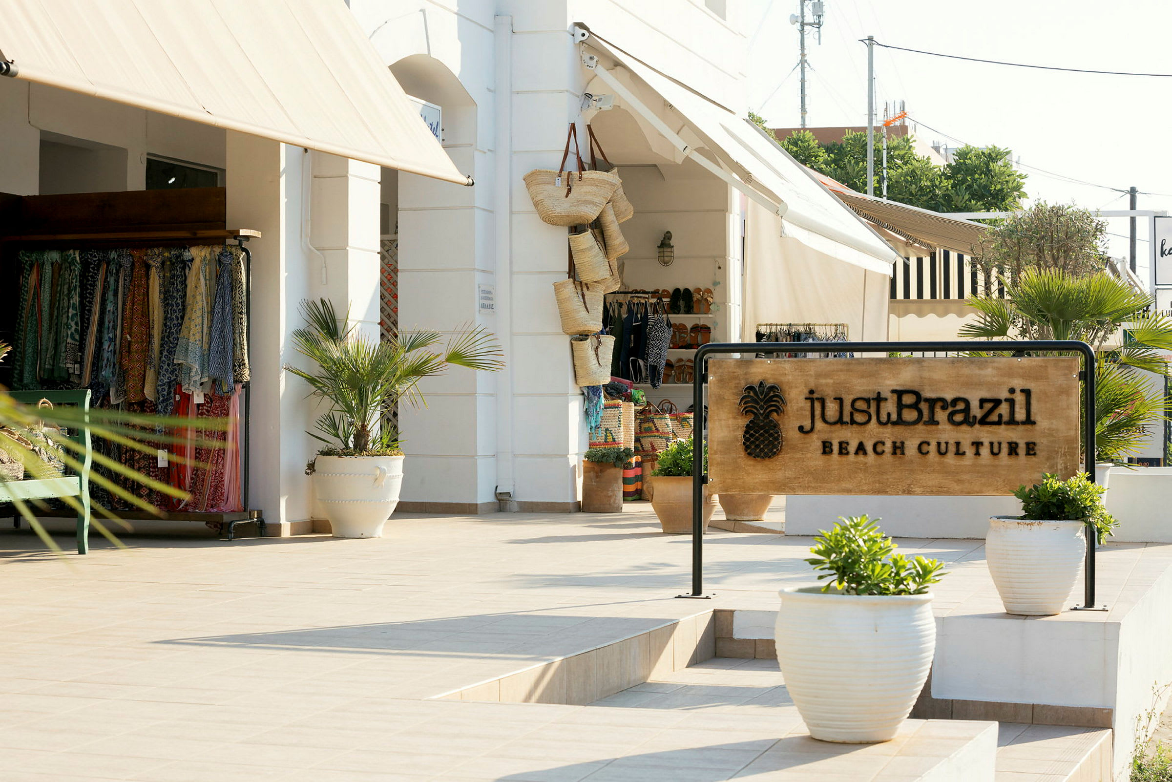Skilt med teksten 'Just Brazil Beach Culture' foran en butikk med bomullsklær og kurver. (AI-generert tekst)