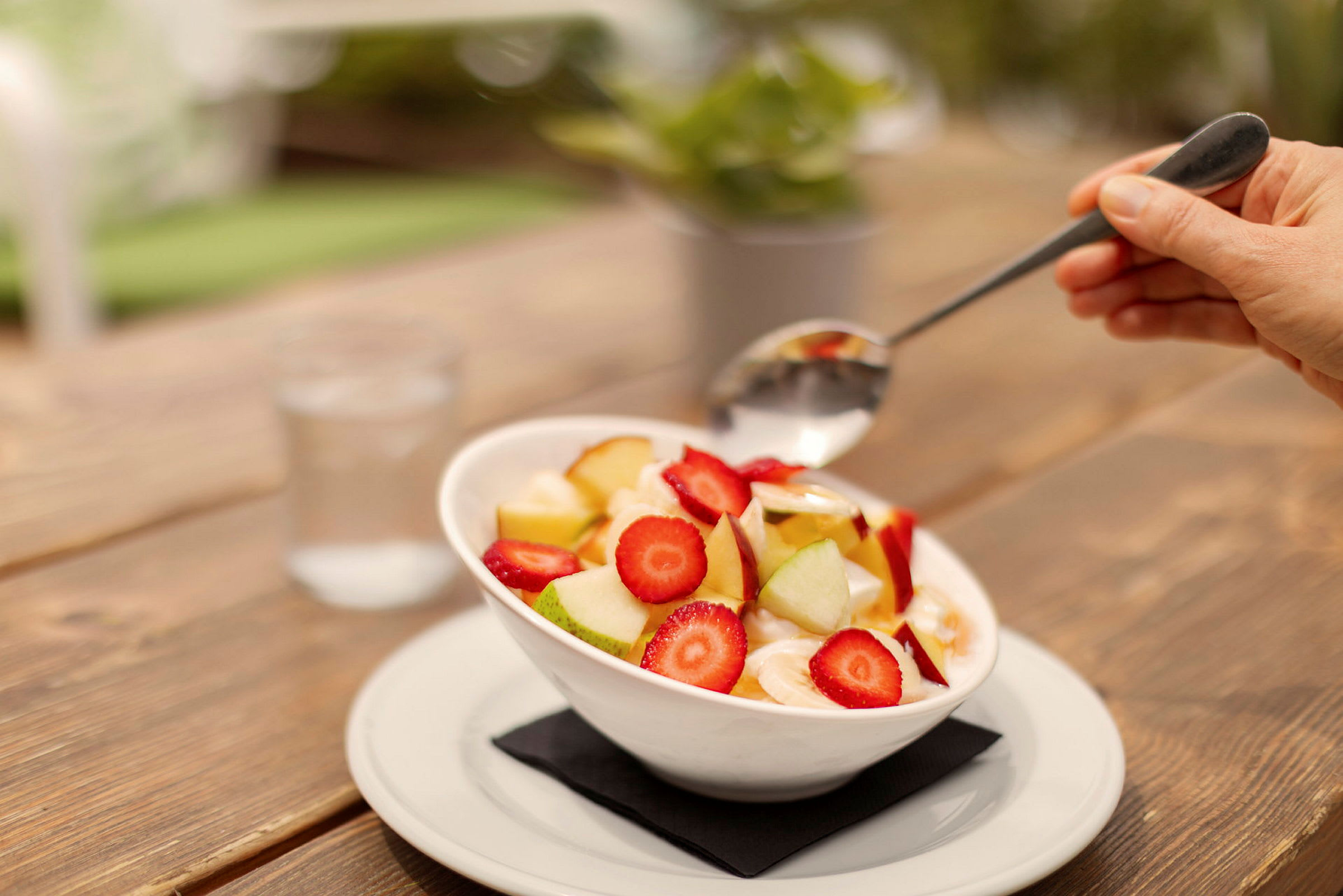 En bolle med fruktsalat som inneholder jordbær, eplebiter og oppskåret banan, servert på et bord. (AI-generert tekst)